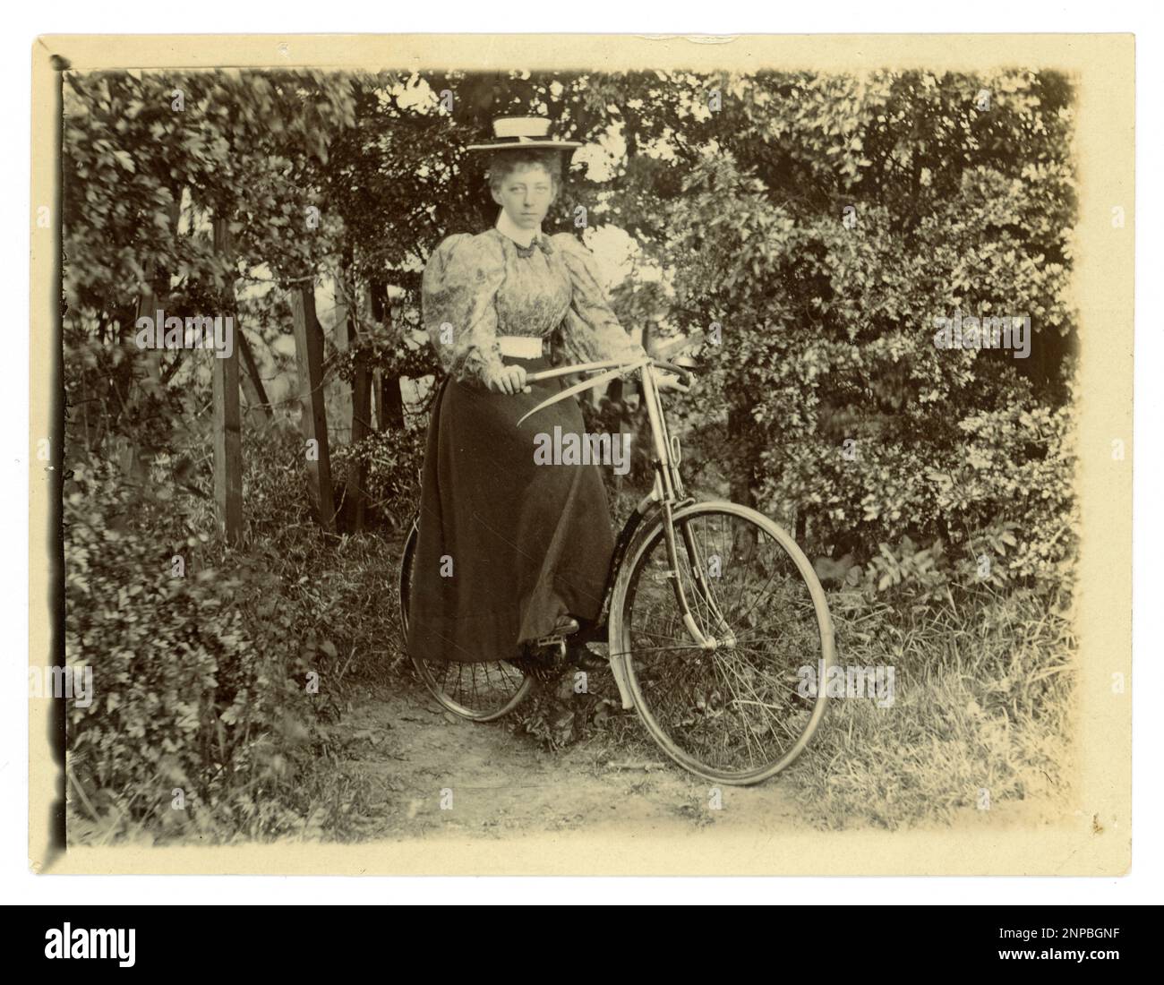 Photographie victorienne originale d'une femme avec son vélo dans un jardin, vélo d'époque, vers 1898, Royaume-Uni Banque D'Images