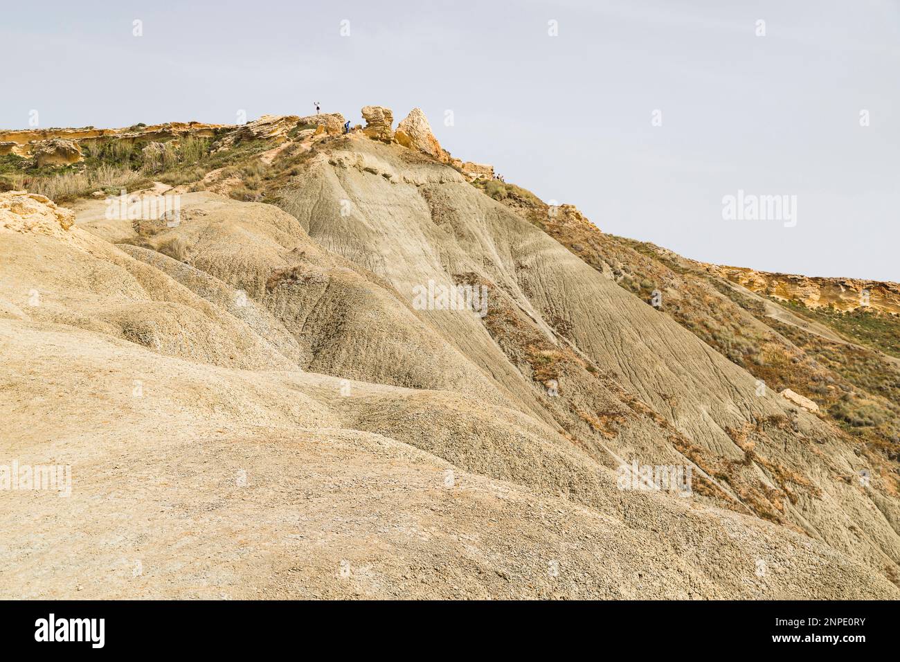 Touristes grimpant sur le paysage lunaire par la baie de Qarraba sur la côte de Malte. Banque D'Images