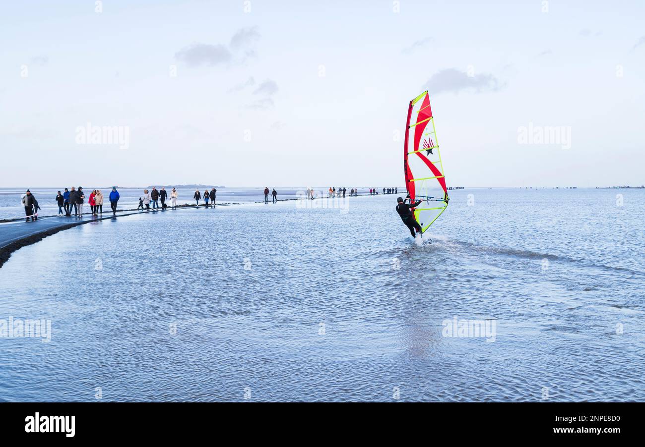 Les marcheurs photographiés autour du bord du lac Marine à West Kirby le 1 janvier 2022 comme un surfeur de vent commence à s'éloigner sur l'eau sur le Wirral. Banque D'Images