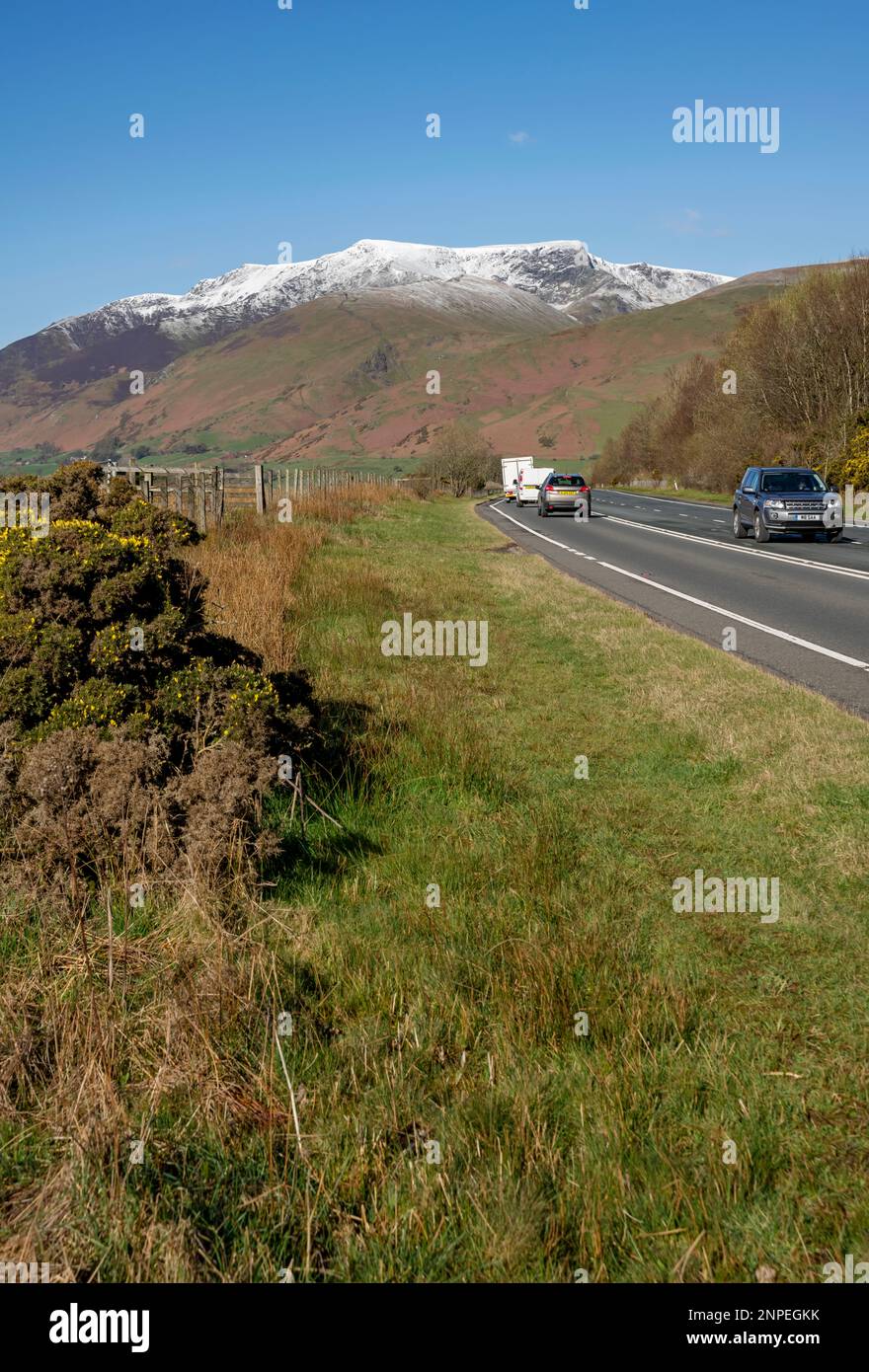La circulation sur la A66 à Keswick et la neige ont surmonté Blencathra au printemps à la fin de l'hiver. Banque D'Images