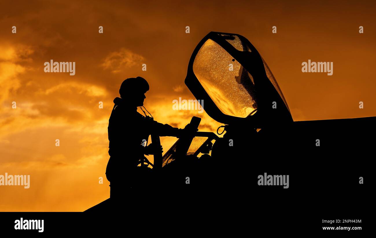 Le pilote de chasse monte à bord de son intercepteur de chasseur à réaction pour une mission d'entraînement au combat au coucher du soleil. Silhouette dramatique de pilote de héros se préparant à la guerre Banque D'Images