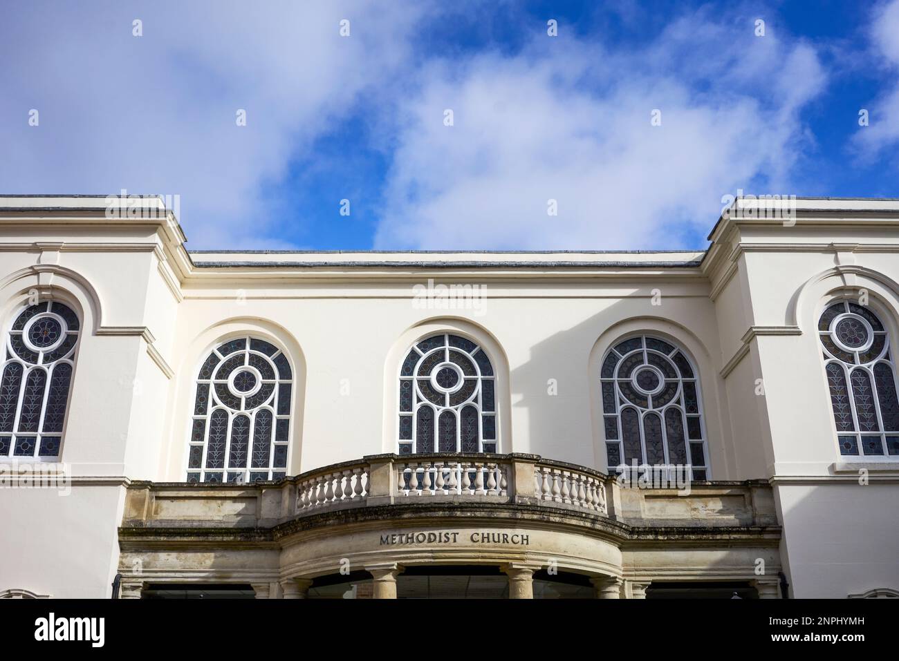 Fenêtres ornées au-dessus de l'entrée d'une église méthodiste avec ciel bleu et nuages derrière Banque D'Images