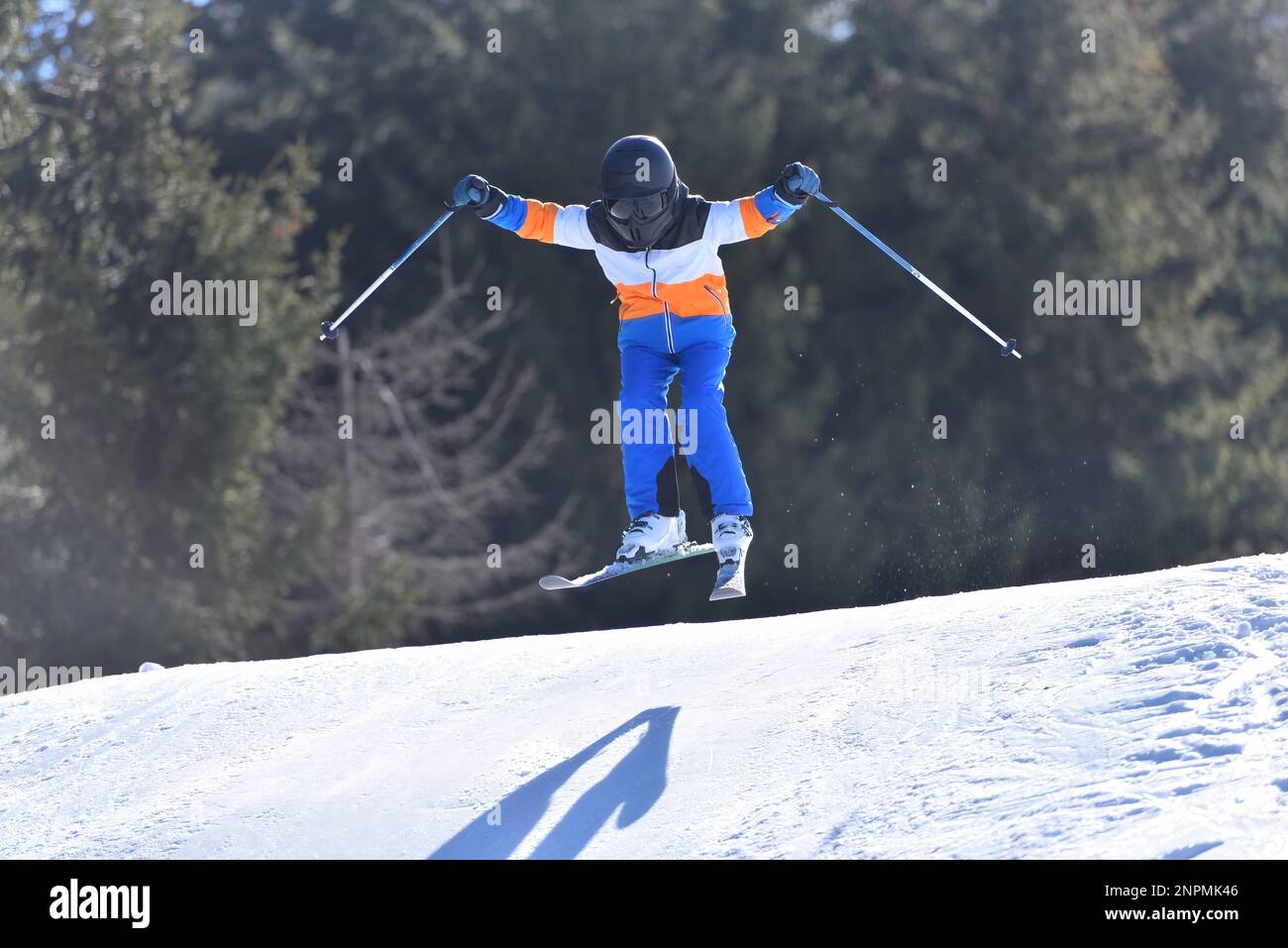 Un skieur osé de 10 ans qui attrape l'air dans un paysage de montagne enneigée Banque D'Images