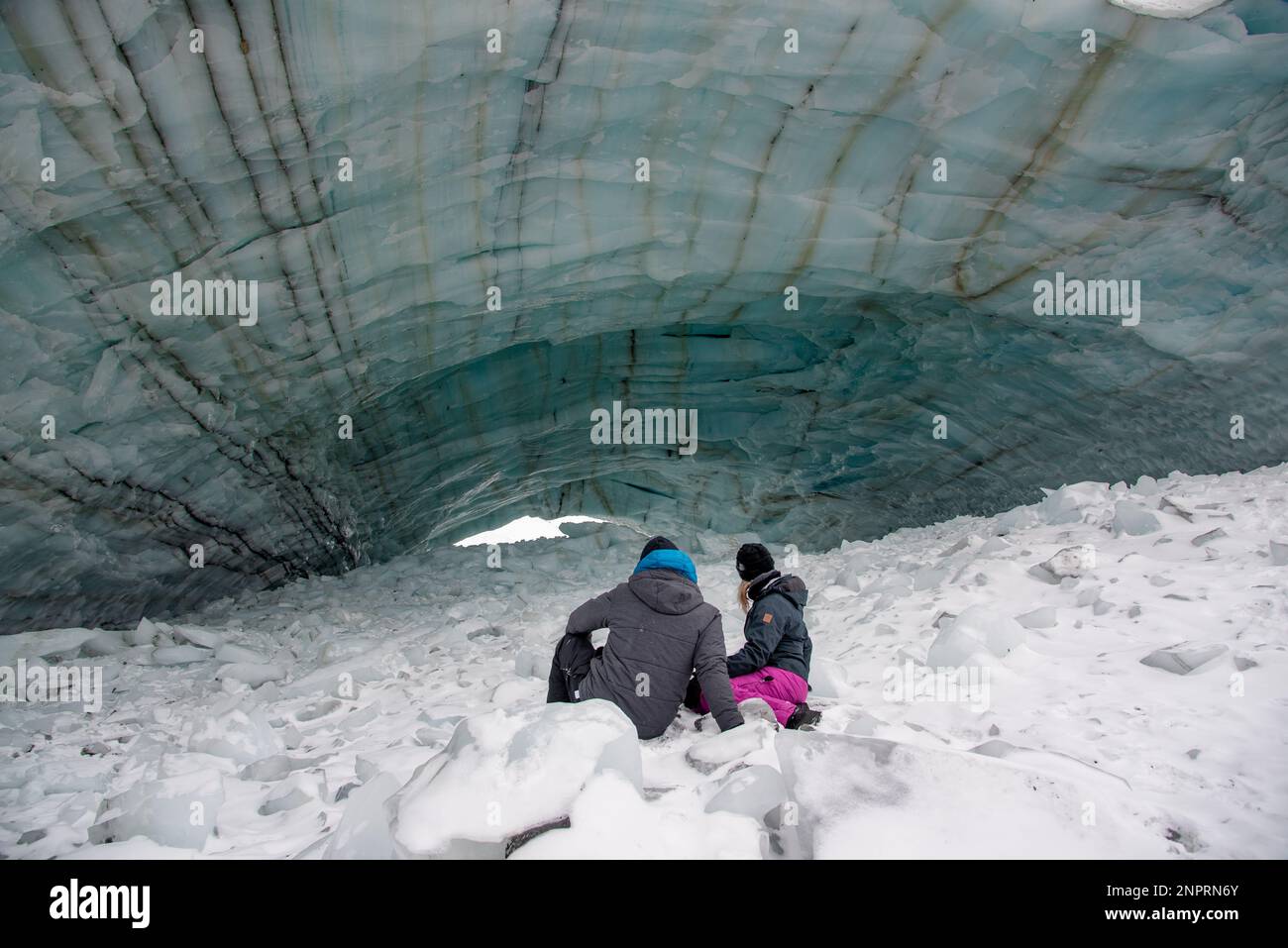 Deux personnes, couple assis à l'extérieur d'une grotte de glace dans le nord du Canada pendant la saison d'hiver. Banque D'Images