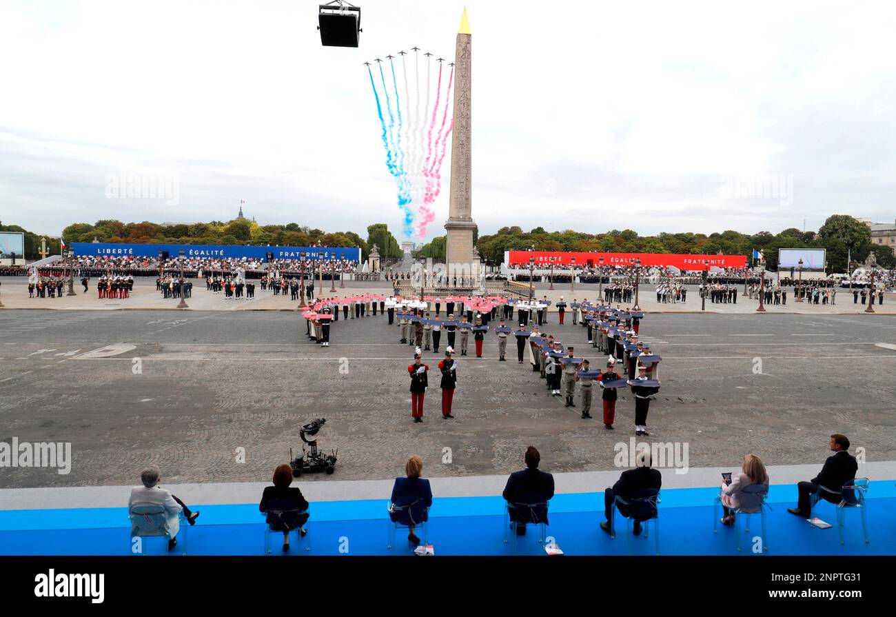 Guests watch French Alpha jets of the Patrouille de France flying over the Champs Elysees avenue during the Bastille Day military ceremony, in Paris, Tuesday, July 14, 2020. France are honoring nurses, ambulance drivers, supermarket cashiers and others on its biggest national holiday Tuesday. Bastille Day's usual grandiose military parade in Paris is being redesigned this year to celebrate heroes of the coronavirus pandemic. (Ludovic Marin, Pool via AP) Banque D'Images