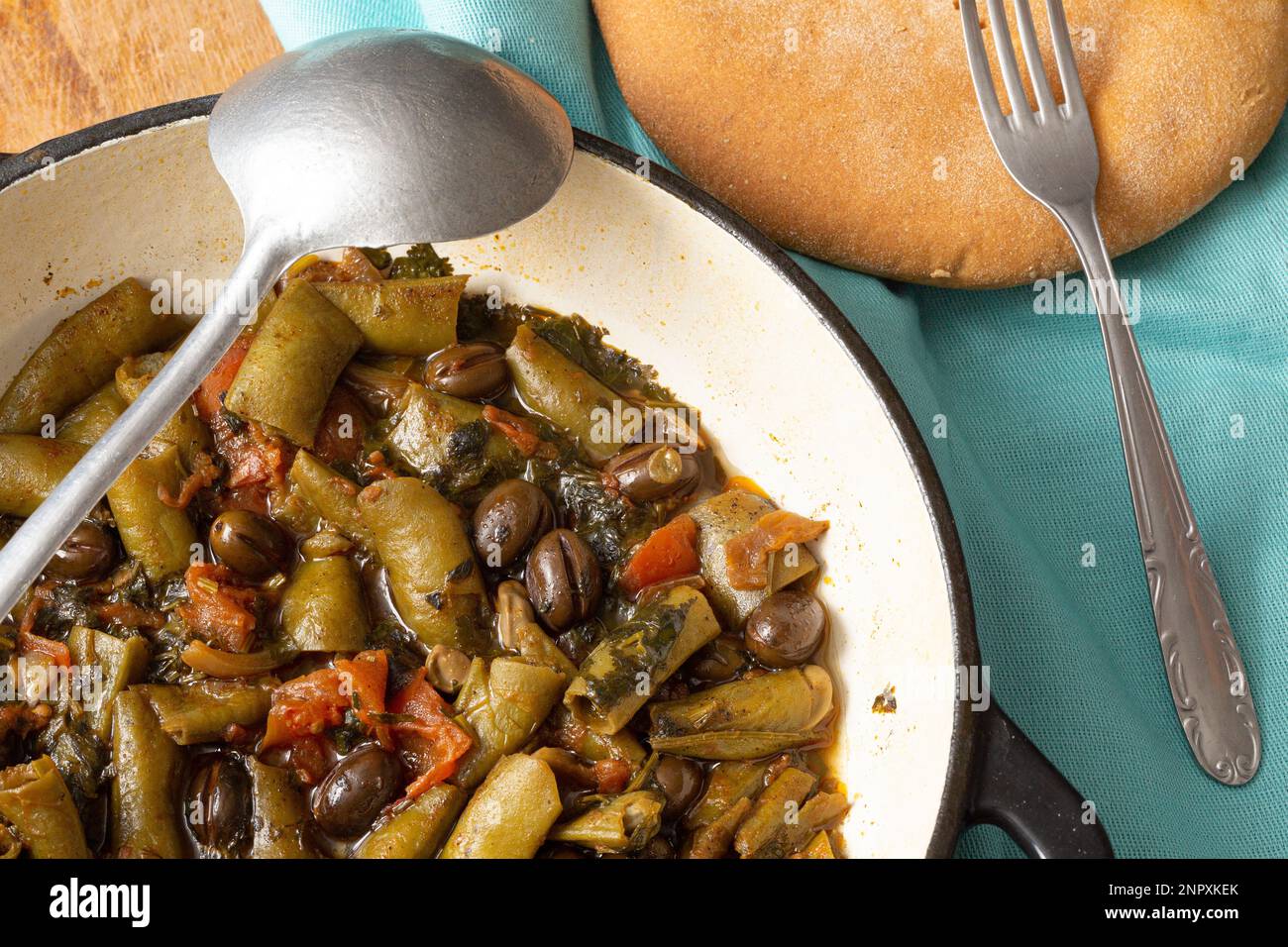 Délicieux ragoût de fèves et d'olives dans une poêle avec cuillère. Rustique, sain, probablement végétalien plat avec du pain. Banque D'Images Délicieux ragoût de fèves et d'olives dans une poêle avec cuillère. Rustique, sain, probablement végétalien plat avec du pain. Banque D'Images