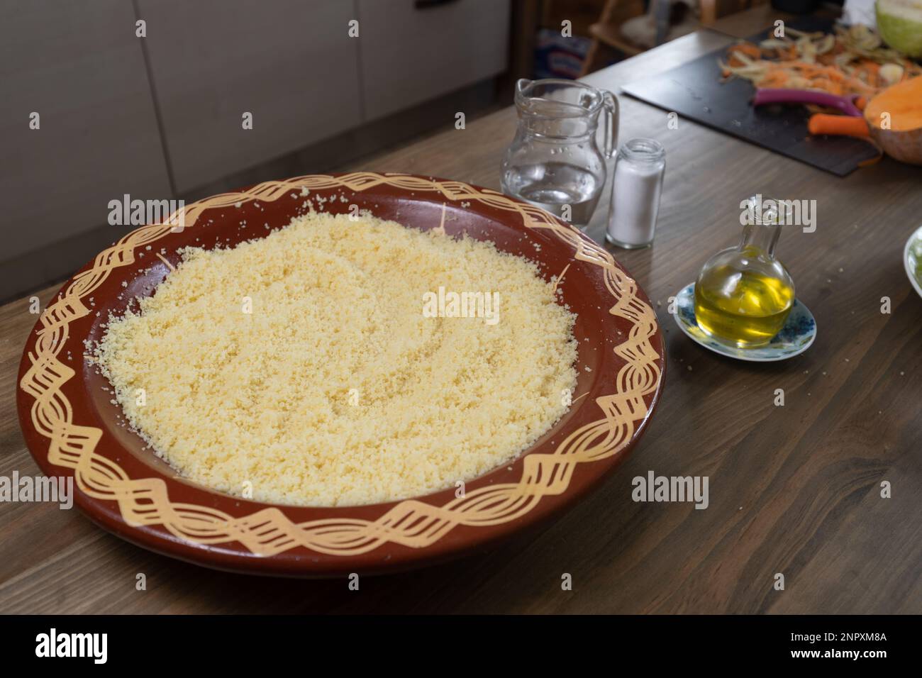 Grains de couscous dans un bol traditionnel avec de l'eau, du sel, de l'huile. Préparation des aliments, ingrédients pour le processus de cuisson. Banque D'Images Grains de couscous dans un bol traditionnel avec de l'eau, du sel, de l'huile. Préparation des aliments, ingrédients pour le processus de cuisson. Banque D'Images