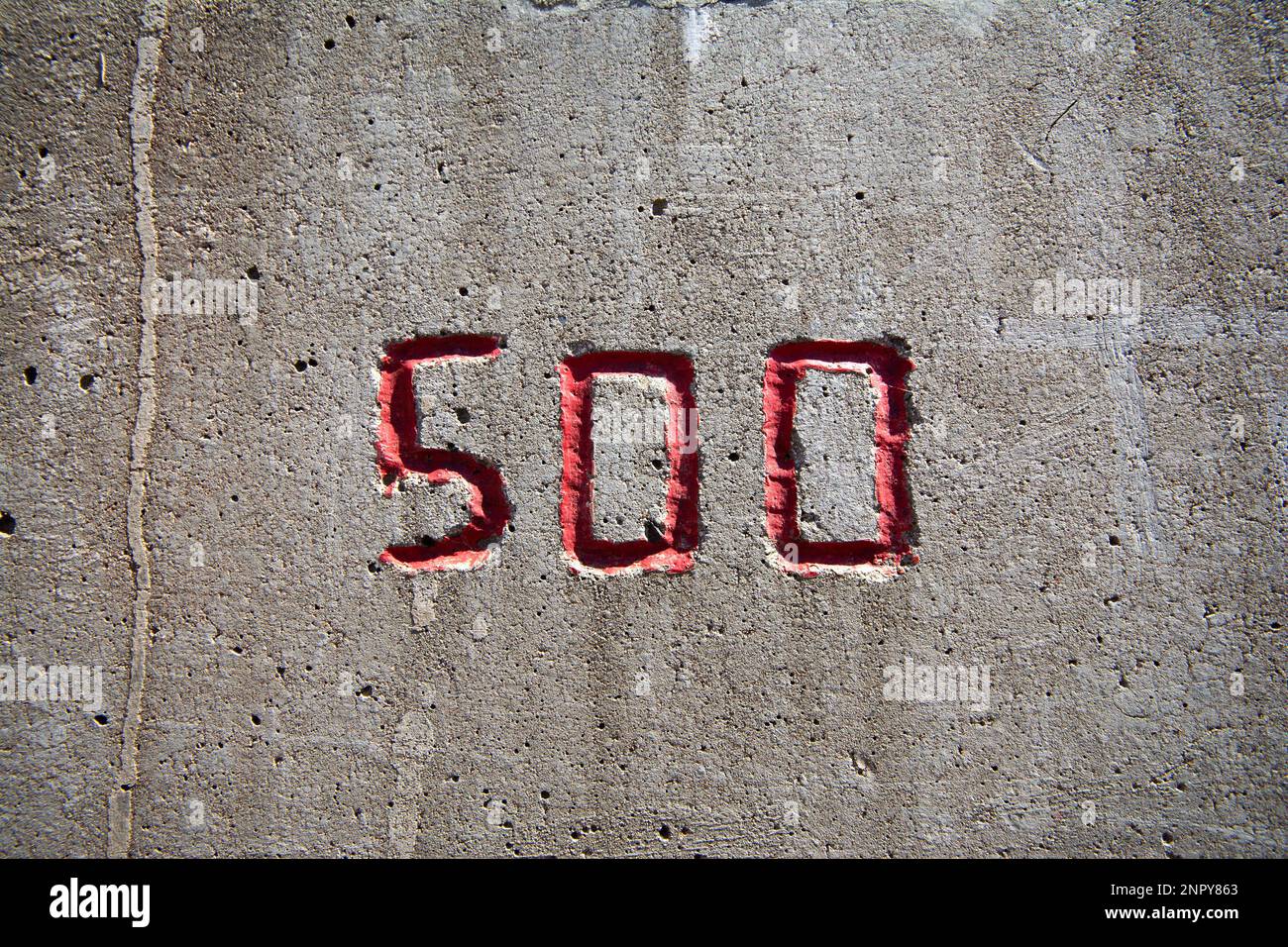 le numéro 500 est sculpté dans un mur en béton en rouge Banque D'Images