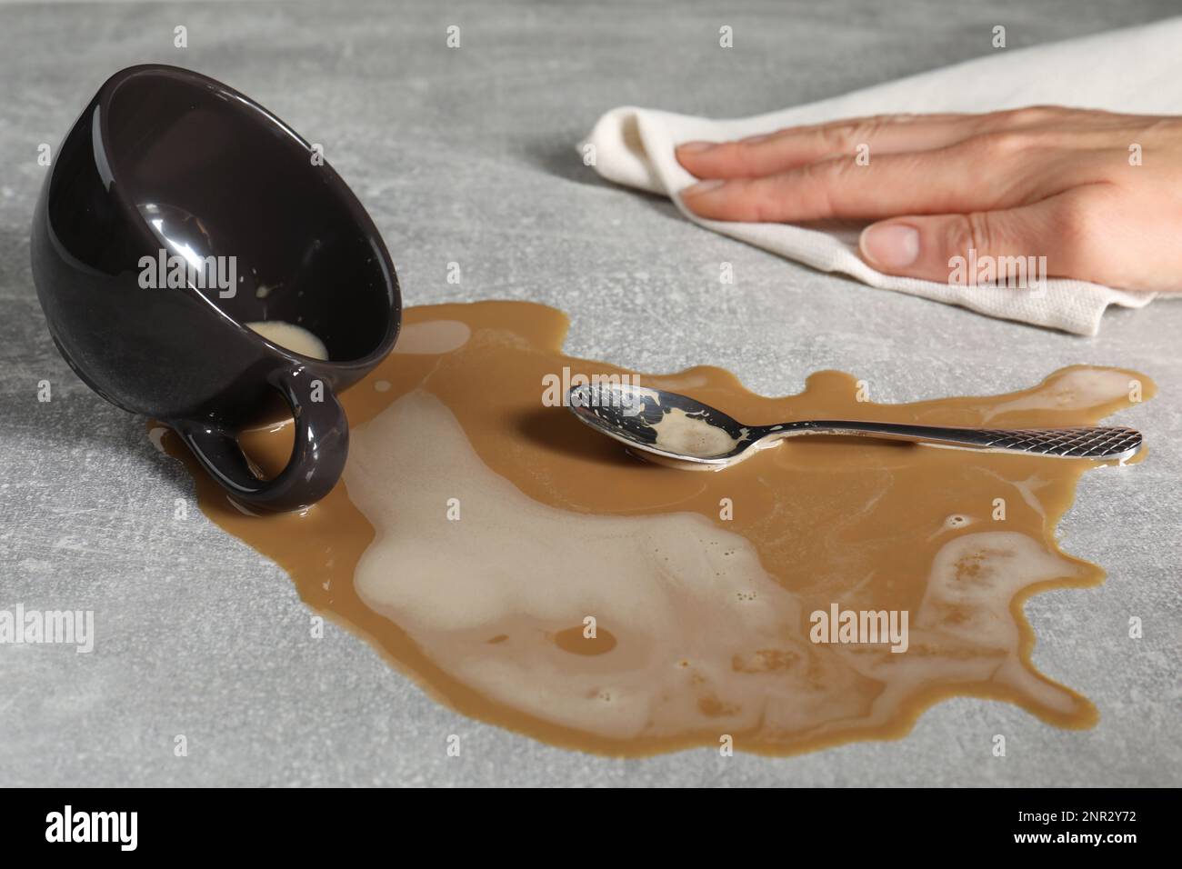Femme essuyant du café renversé sur une table grise, gros plan Banque D'Images