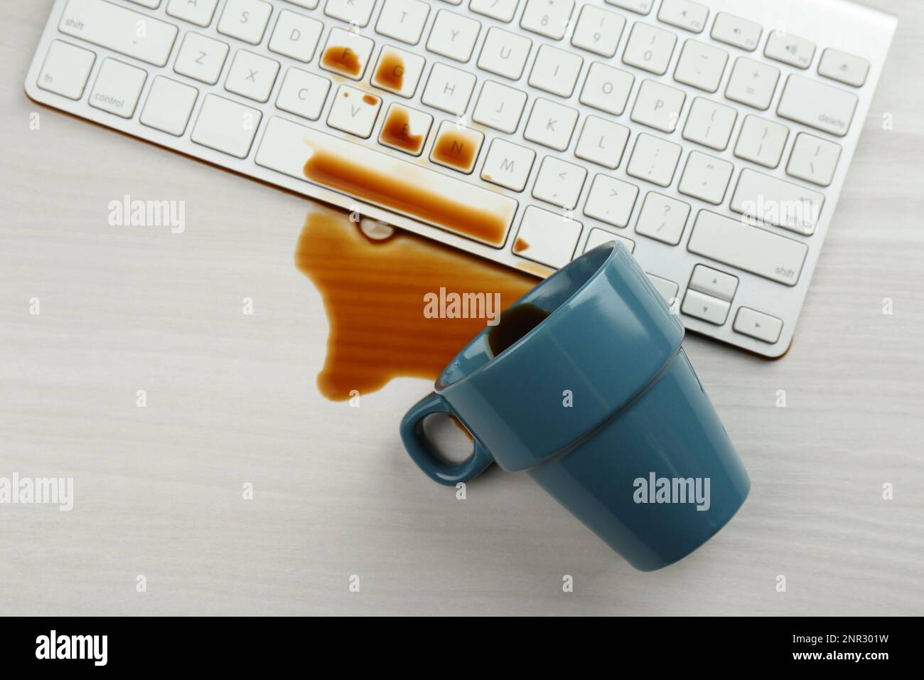 Tasse de café renversé sur le clavier de l'ordinateur sur une table en bois blanc, plat Banque D'Images Tasse de café renversé sur le clavier de l'ordinateur sur une table en bois blanc, plat Banque D'Images