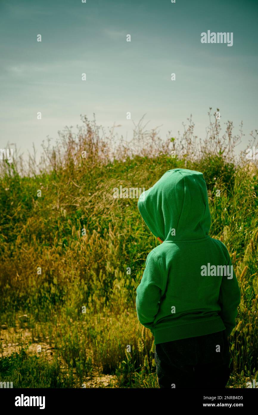 Vue arrière d'un garçon de 6 ans à capuche dans la campagne Banque D'Images