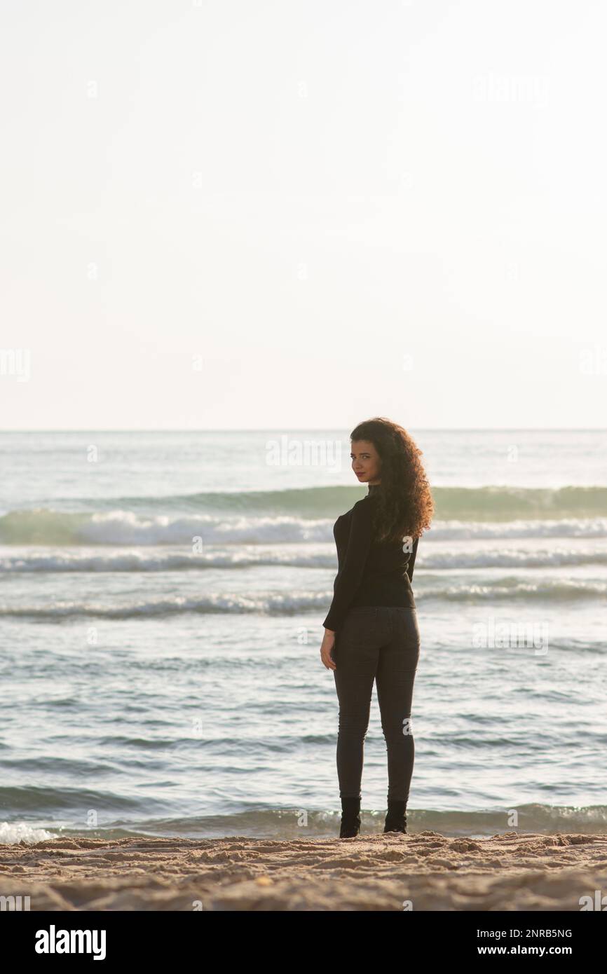 Jeune femme debout sur la plage et regardant sur l'épaule Banque D'Images