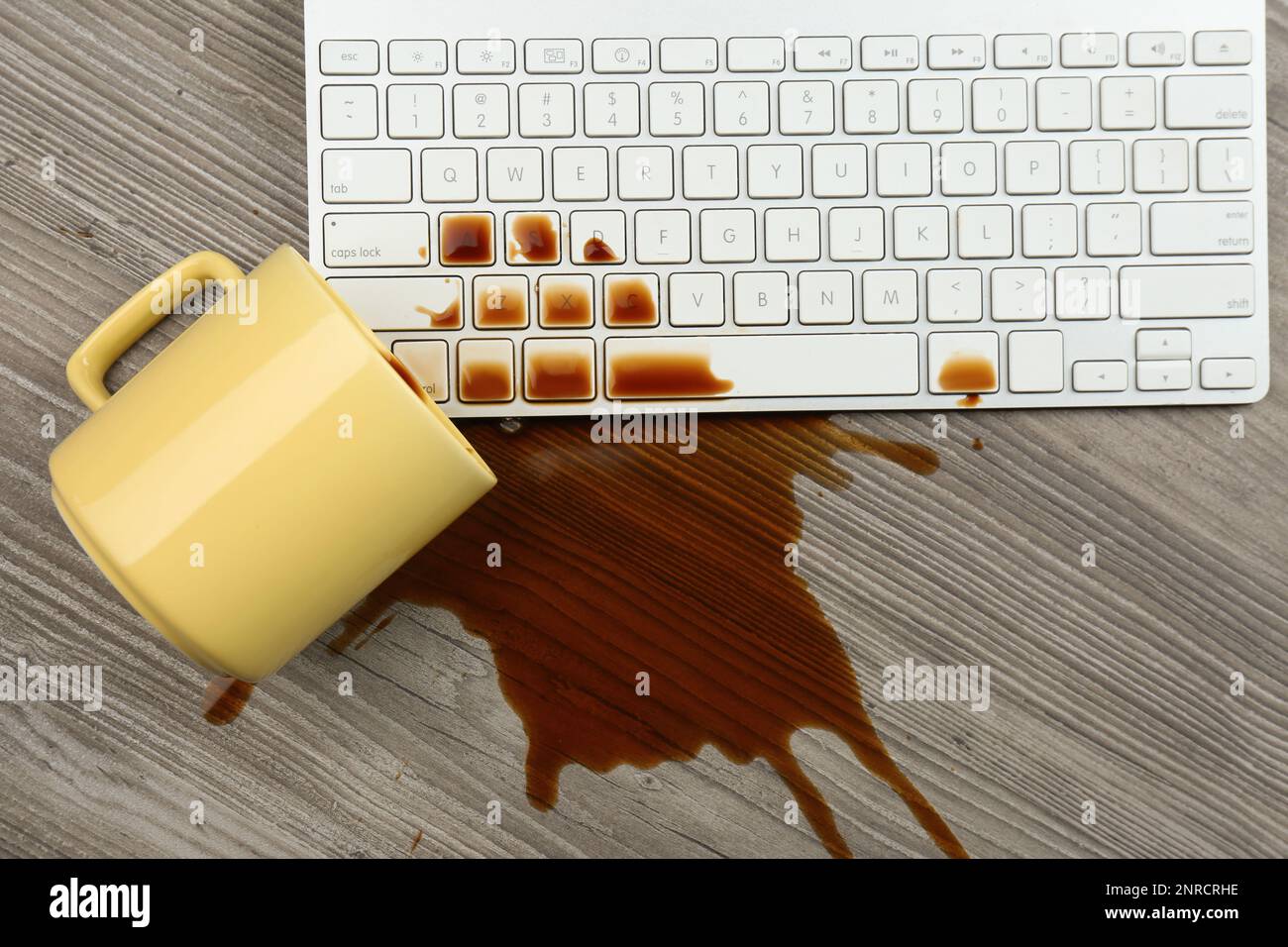 Tasse de café renversé sur le clavier de l'ordinateur sur une table en bois, plat Banque D'Images Tasse de café renversé sur le clavier de l'ordinateur sur une table en bois, plat Banque D'Images