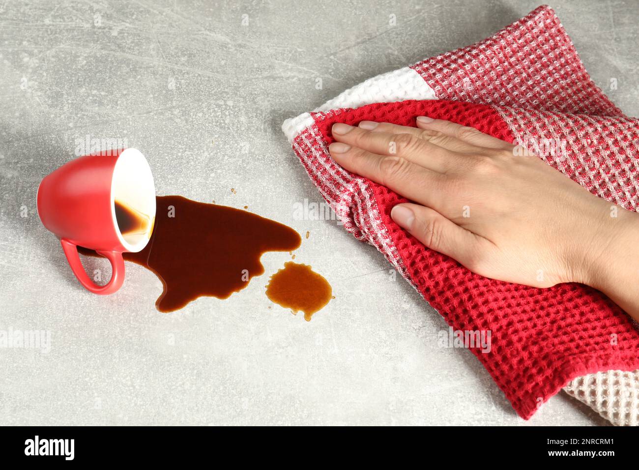 Femme essuyant du café renversé sur une table grise, gros plan Banque D'Images
