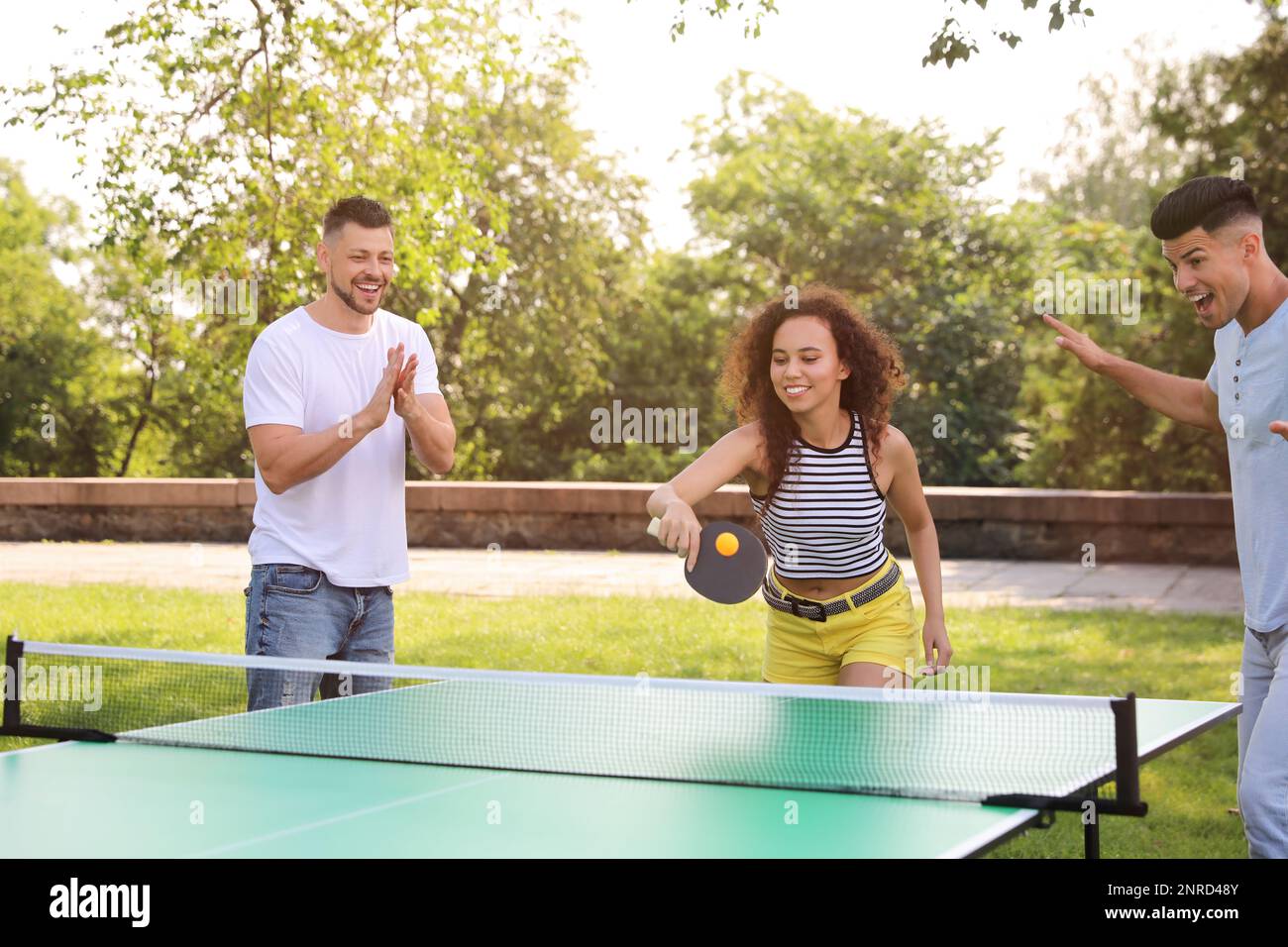 Amis jouant au ping-pong à l'extérieur le jour de l'été Banque D'Images