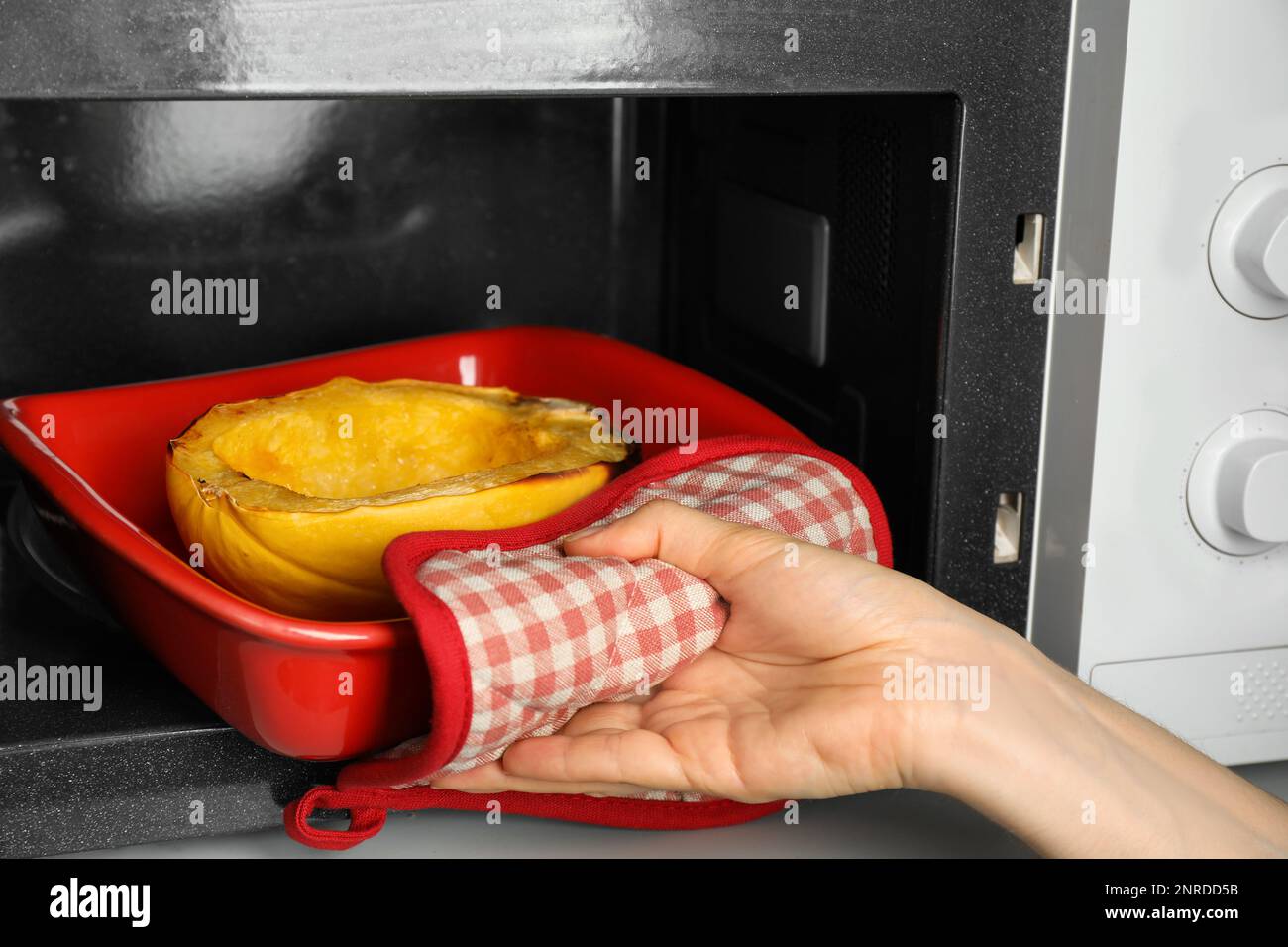 Femme prenant des spaghetti de squash cuit hors du four à micro-ondes, gros plan Banque D'Images