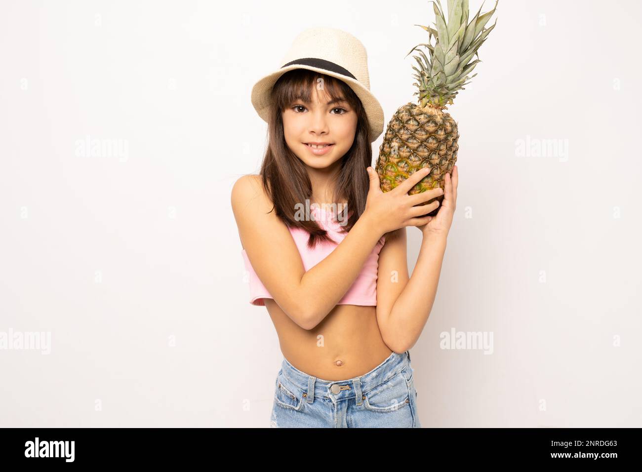 Petite fille en vêtements d'été isolée tenant l'ananas Photo Stock - Alamy