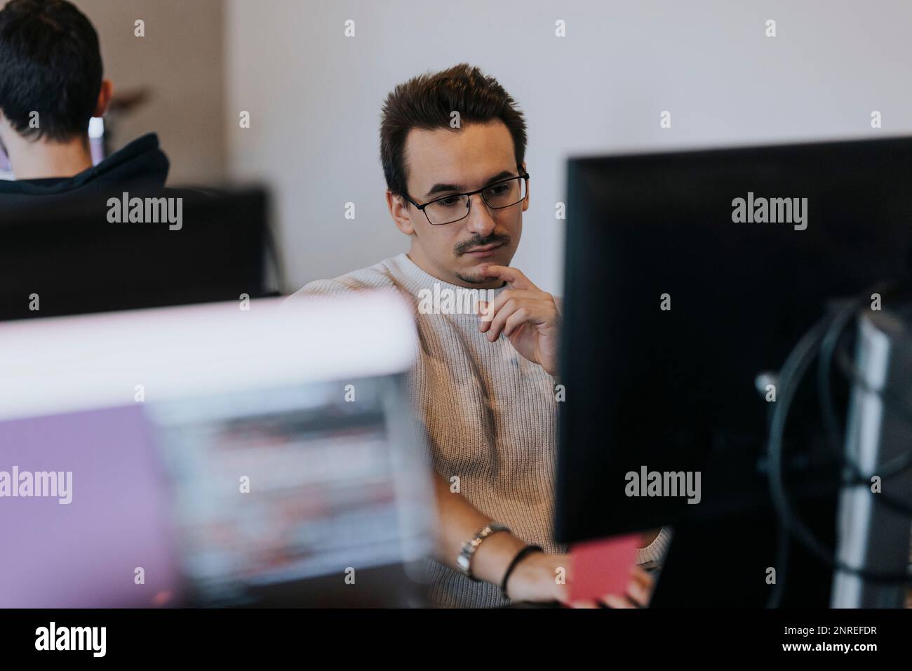 Homme d'affaires dévoué travaillant sur l'ordinateur sur un lieu de travail créatif Banque D'Images