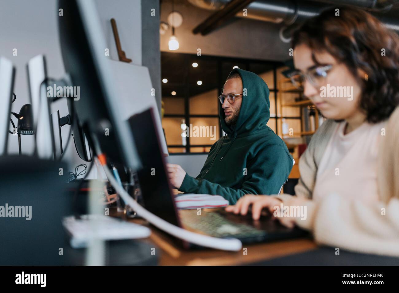Jeune programmeur travaillant par une collègue féminine à un bureau de création Banque D'Images