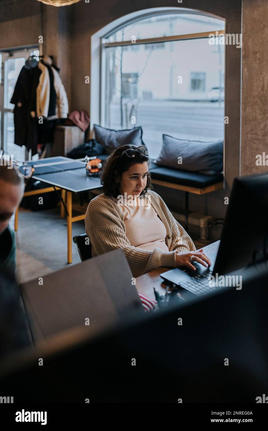 Une jeune femme hacker travaille sur un ordinateur portable par un collègue de la start-up Banque D'Images