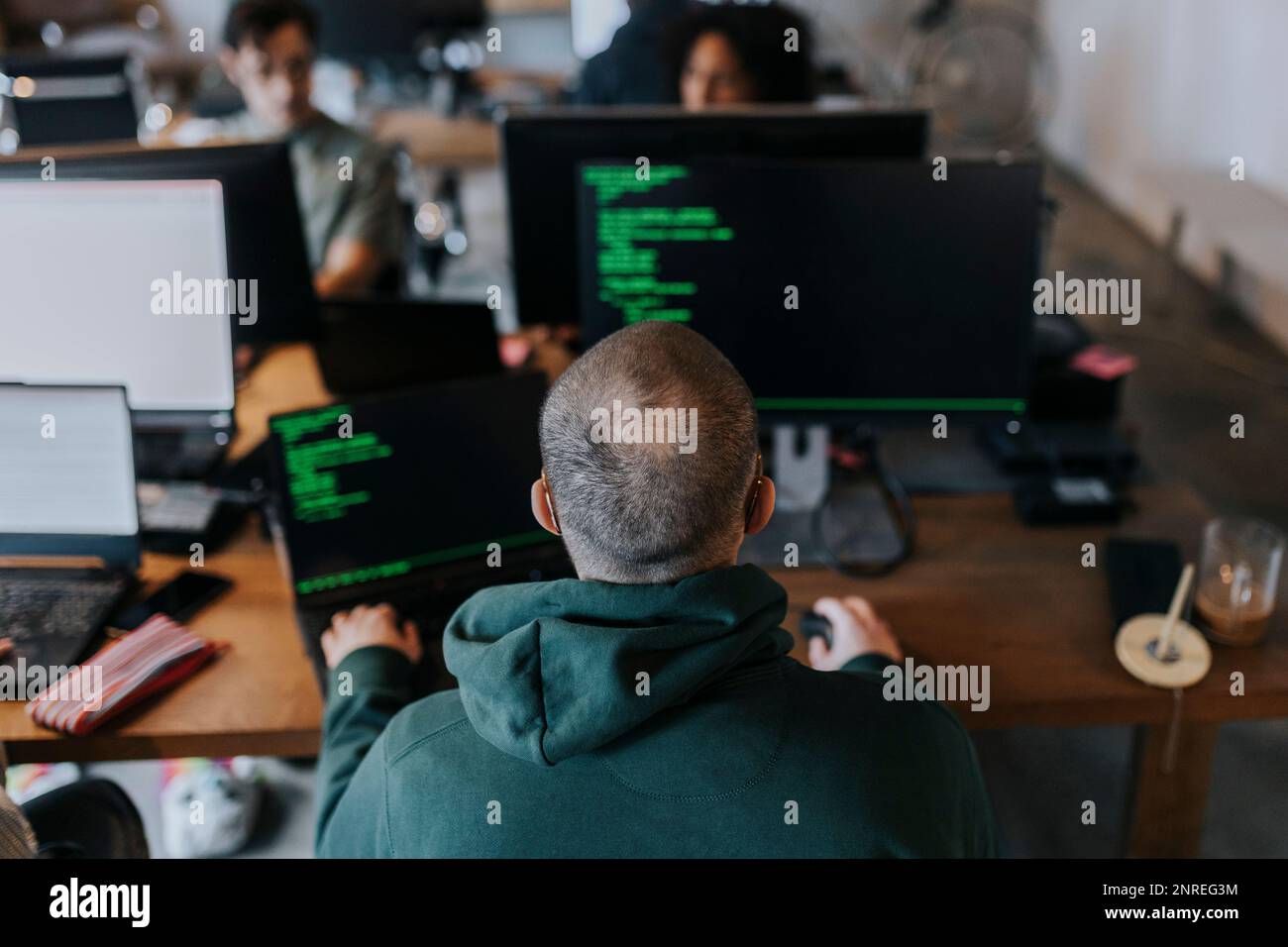 Vue arrière du programmateur mâle codant sur l'ordinateur au bureau de création Banque D'Images