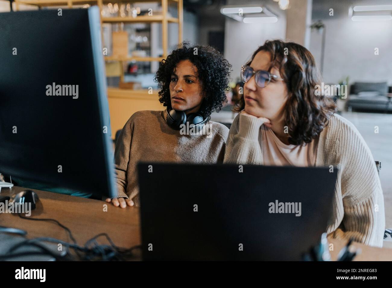 Des femmes programmeurs dédiées utilisant l'ordinateur tout en travaillant à un bureau dans un lieu de travail créatif Banque D'Images