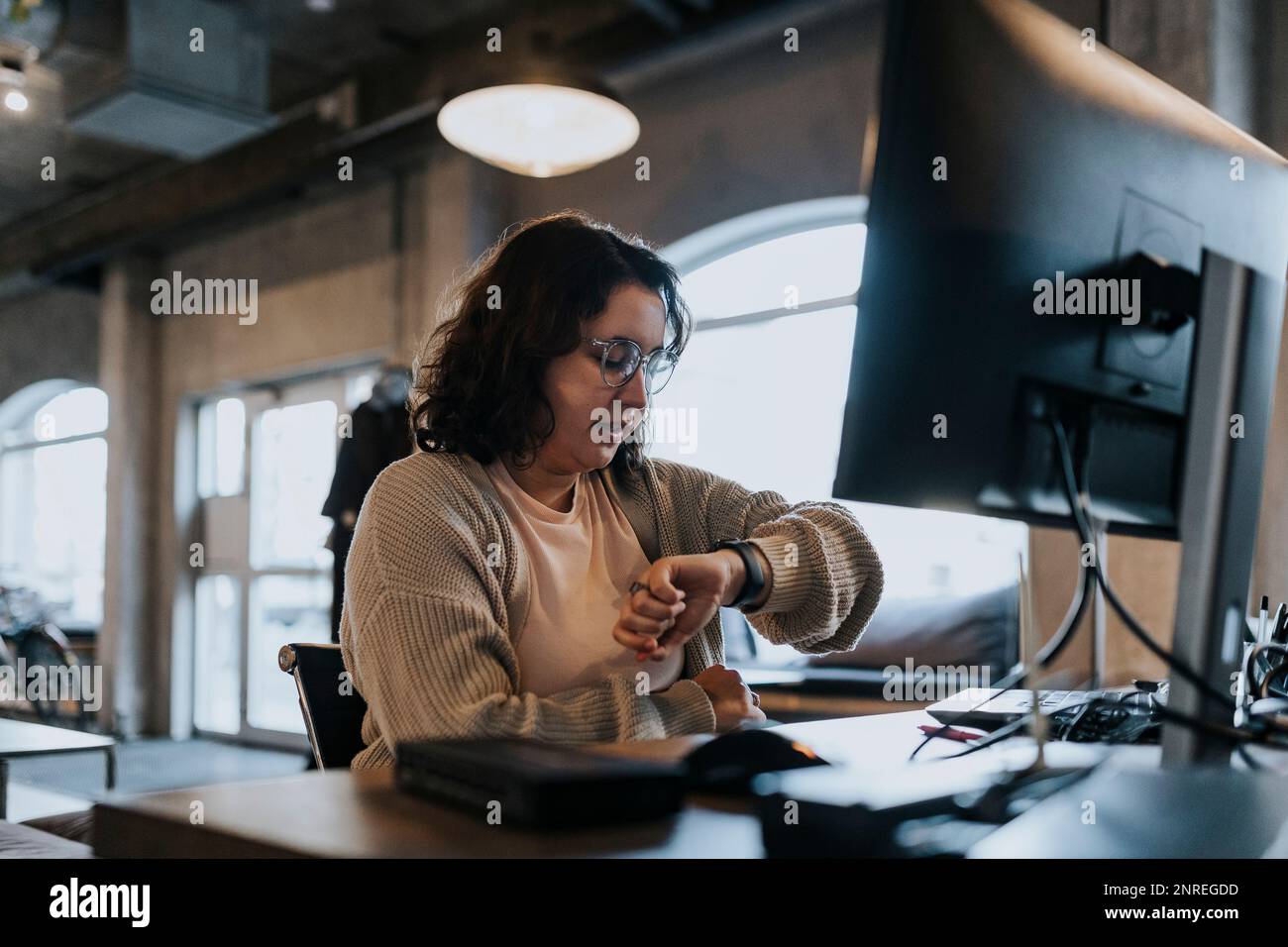 Une femme programmeuse vérifie le temps sur la montre-bracelet tout en travaillant à la start-up Banque D'Images