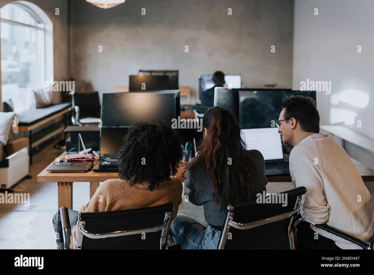 Vue arrière des programmeurs informatiques multiraciaux discutant au bureau de création Banque D'Images
