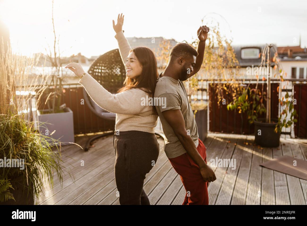Vue latérale de couple dansant sans souci tout en se tenant dos à dos sur la terrasse Banque D'Images