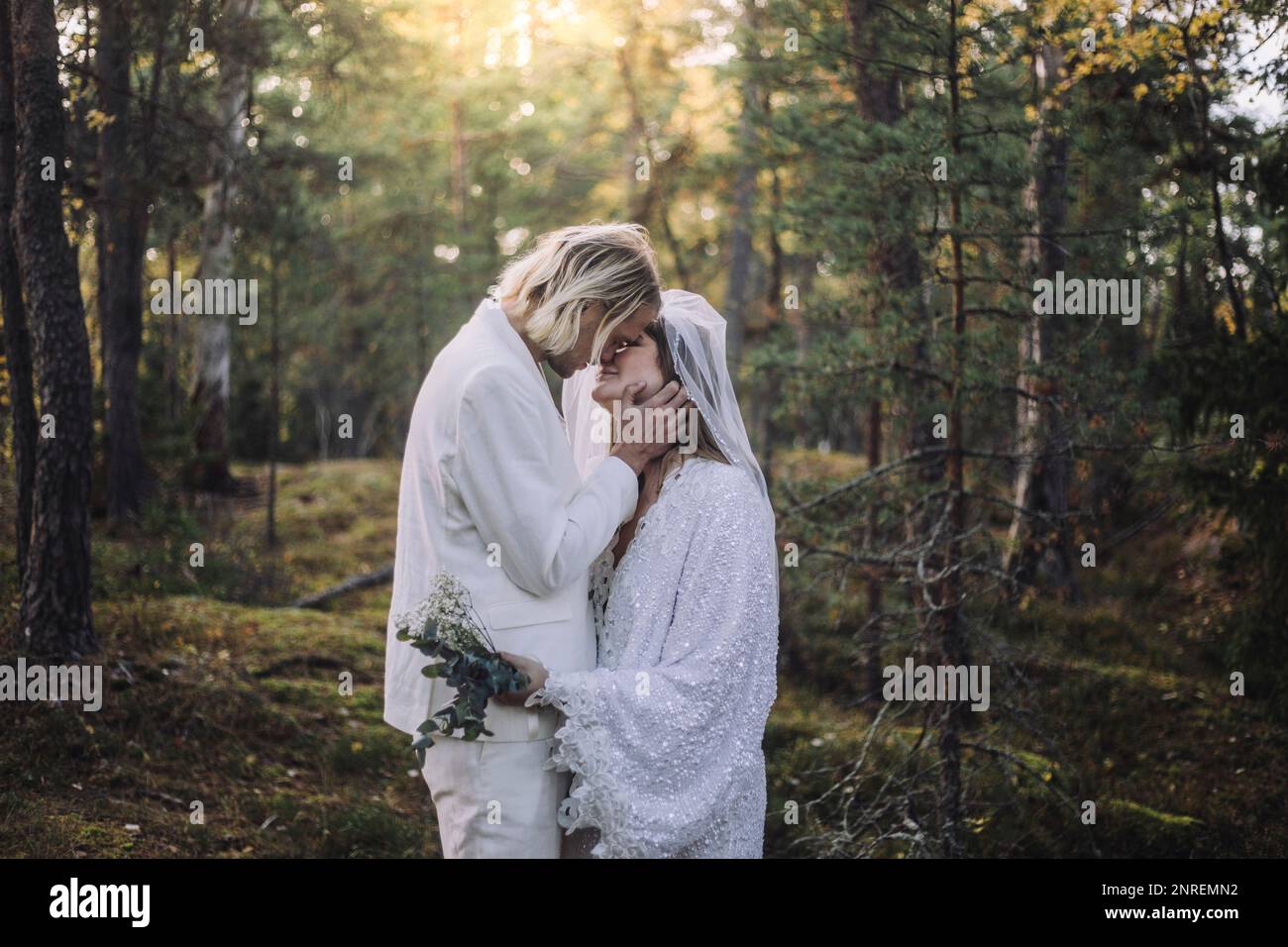 Couple récemment marié s'embrassant dans la forêt le jour du mariage Banque D'Images