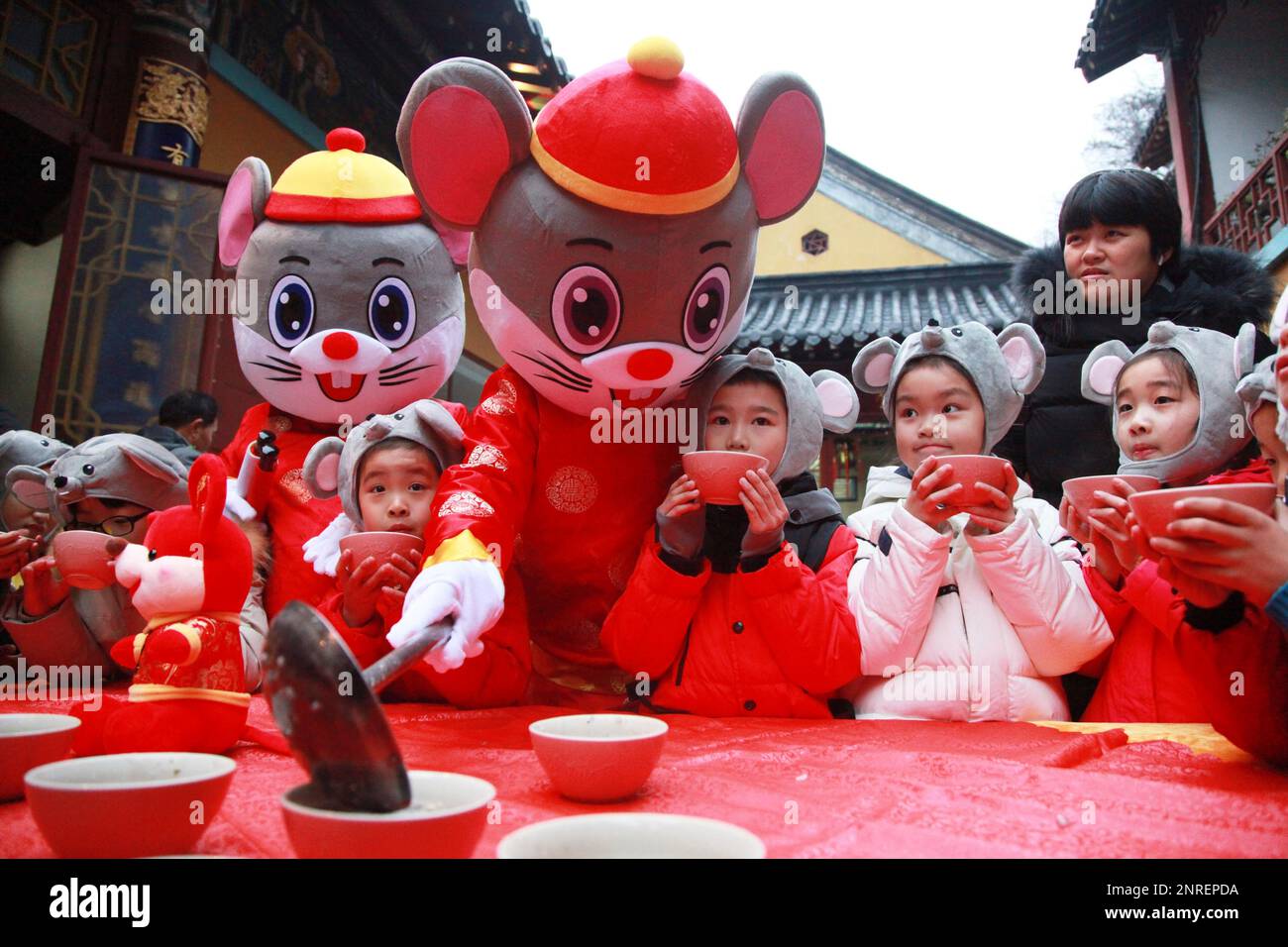 Two volunteers in mouse costumes deliver Laba porridge to children visiting Xuanzang Temple in Nanjing in east China's Jiangsu province Thursday, Jan. 02, 2020, a traditional event on the eighth day of the last lunar month. The coming Chinese new year is a Year of the Mouse. (FeatureChina via AP Images) Banque D'Images