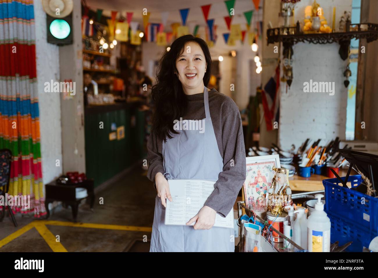 Portrait d'une femme souriante tenant une carte de menu au restaurant Banque D'Images