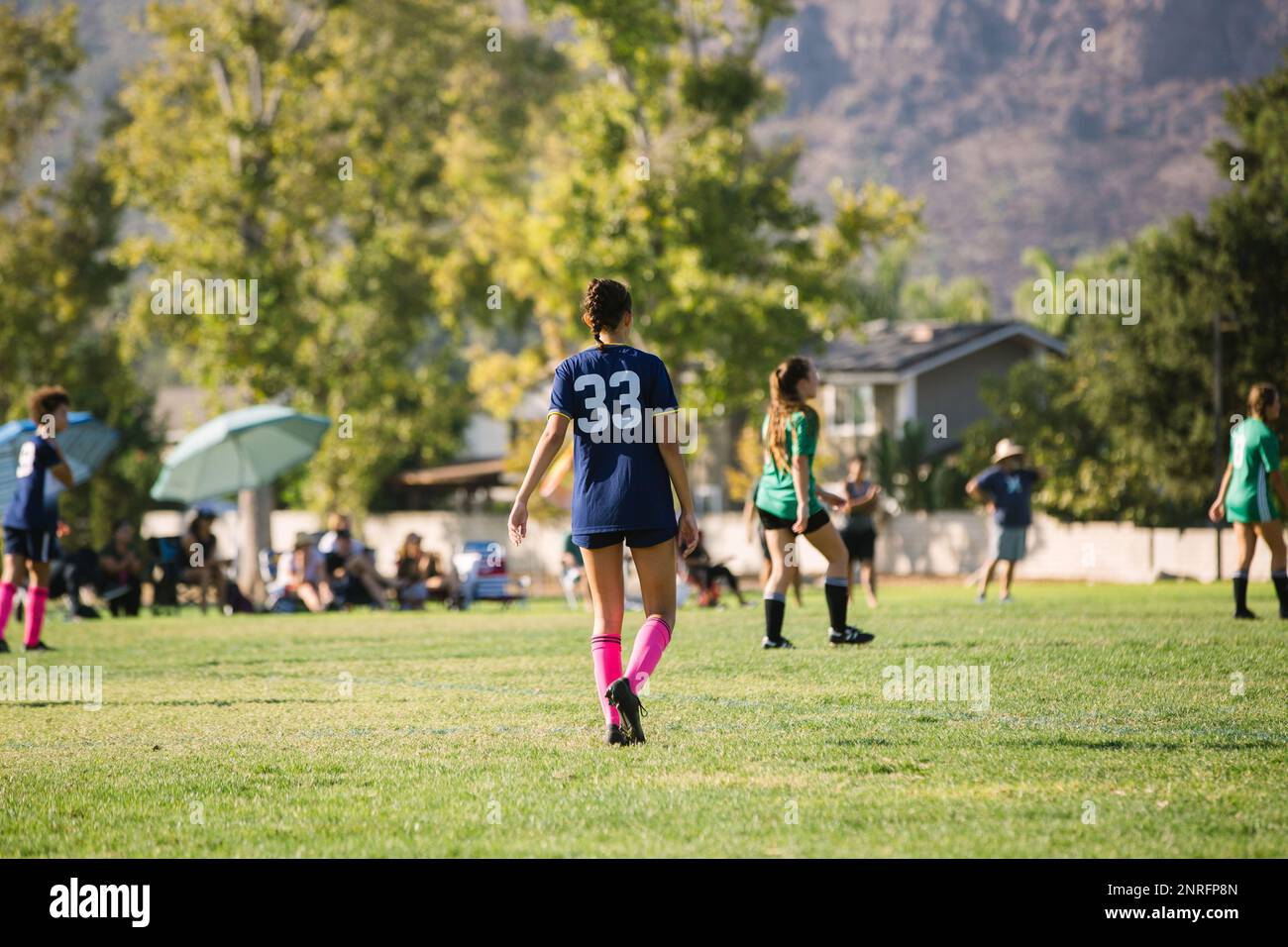 Arrière de la fille joueur de football marchant sur le terrain Banque D'Images