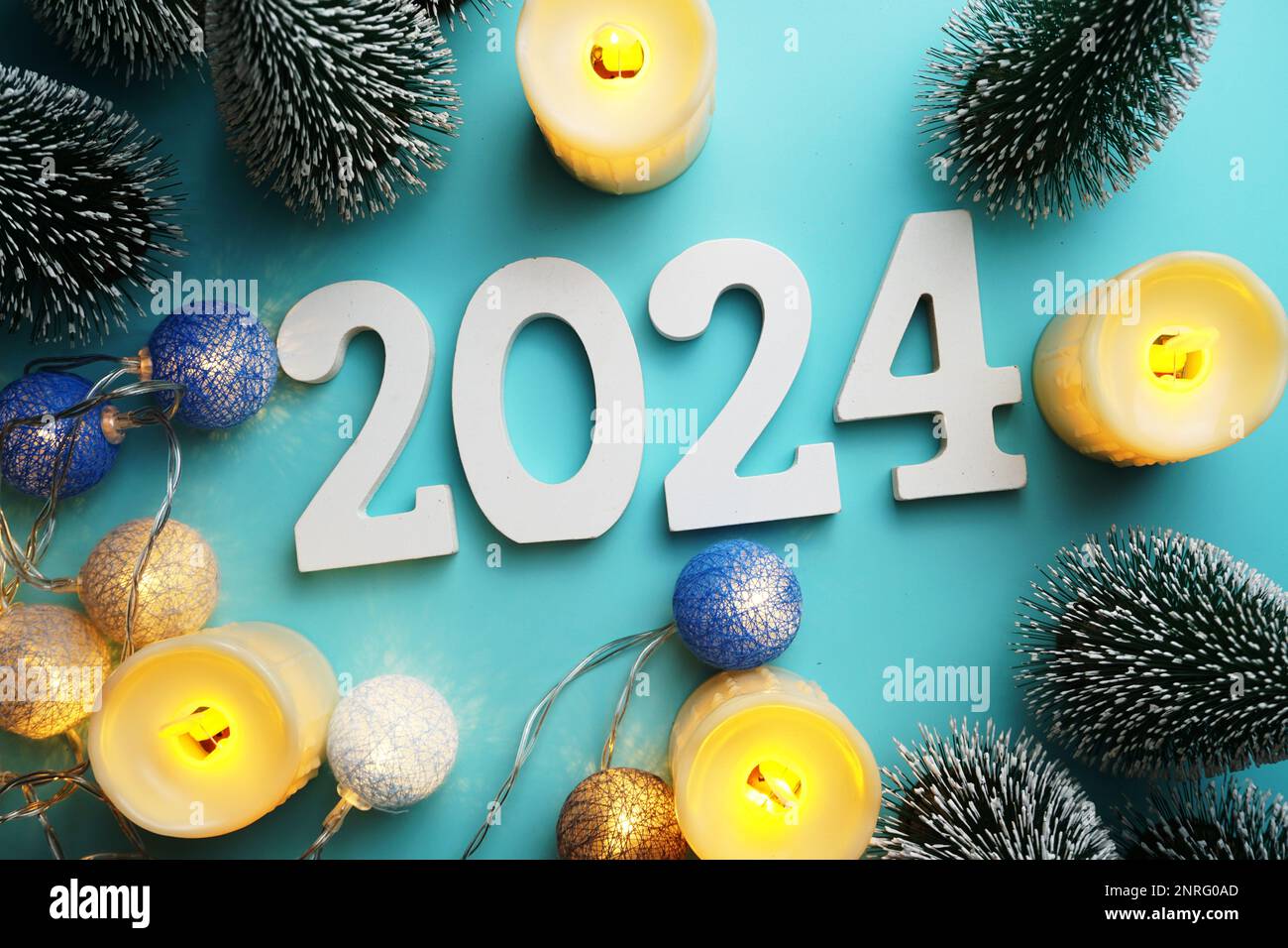 2024 bonne année avec arbre de Noël et bougies LED sur fond bleu Photo Stock Alamy