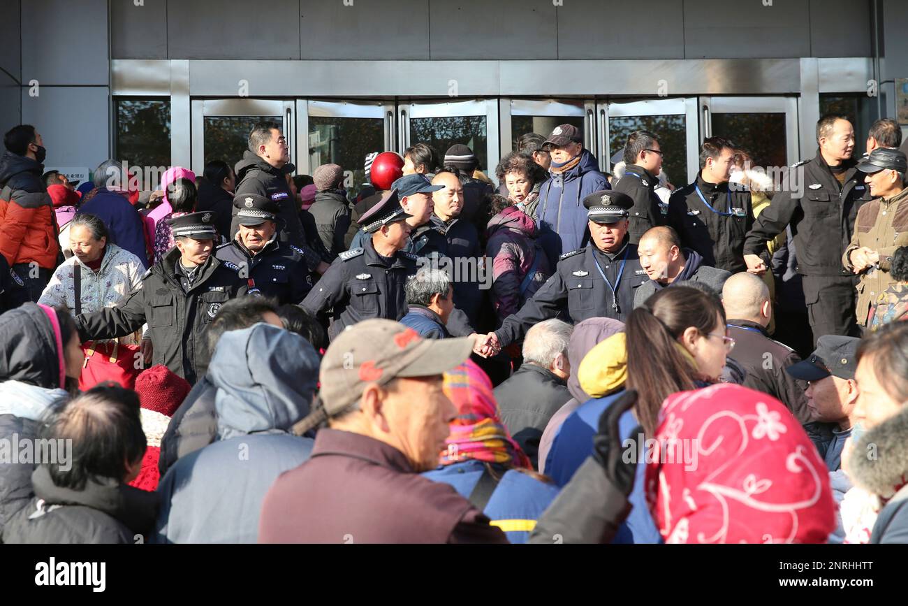 Security guards keep the order of the crowd coming to buy China's first non-circle commemorative coins outside a bank outlet in Nantong in east China's Jiangsu province Friday, Dec. 06, 2019. PBOC issued 120 million such coins, and the souvenir market price is now over three times of the bank price. (FeatureChina via AP Images) Banque D'Images