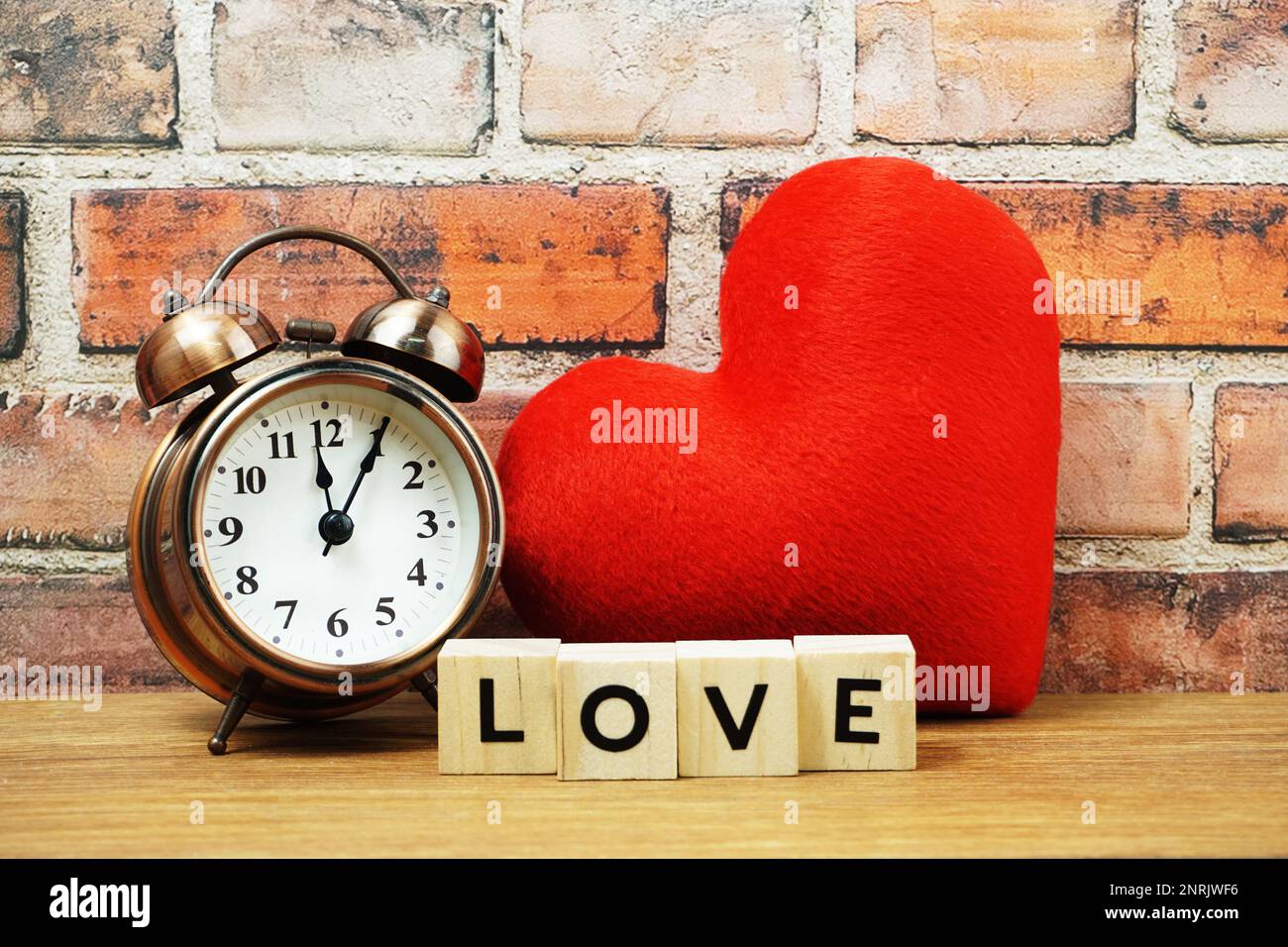 Bonne Saint Valentin avec lettre de l'alphabet d'amour avec réveil et coeur rouge sur fond de mur de brique Banque D'Images