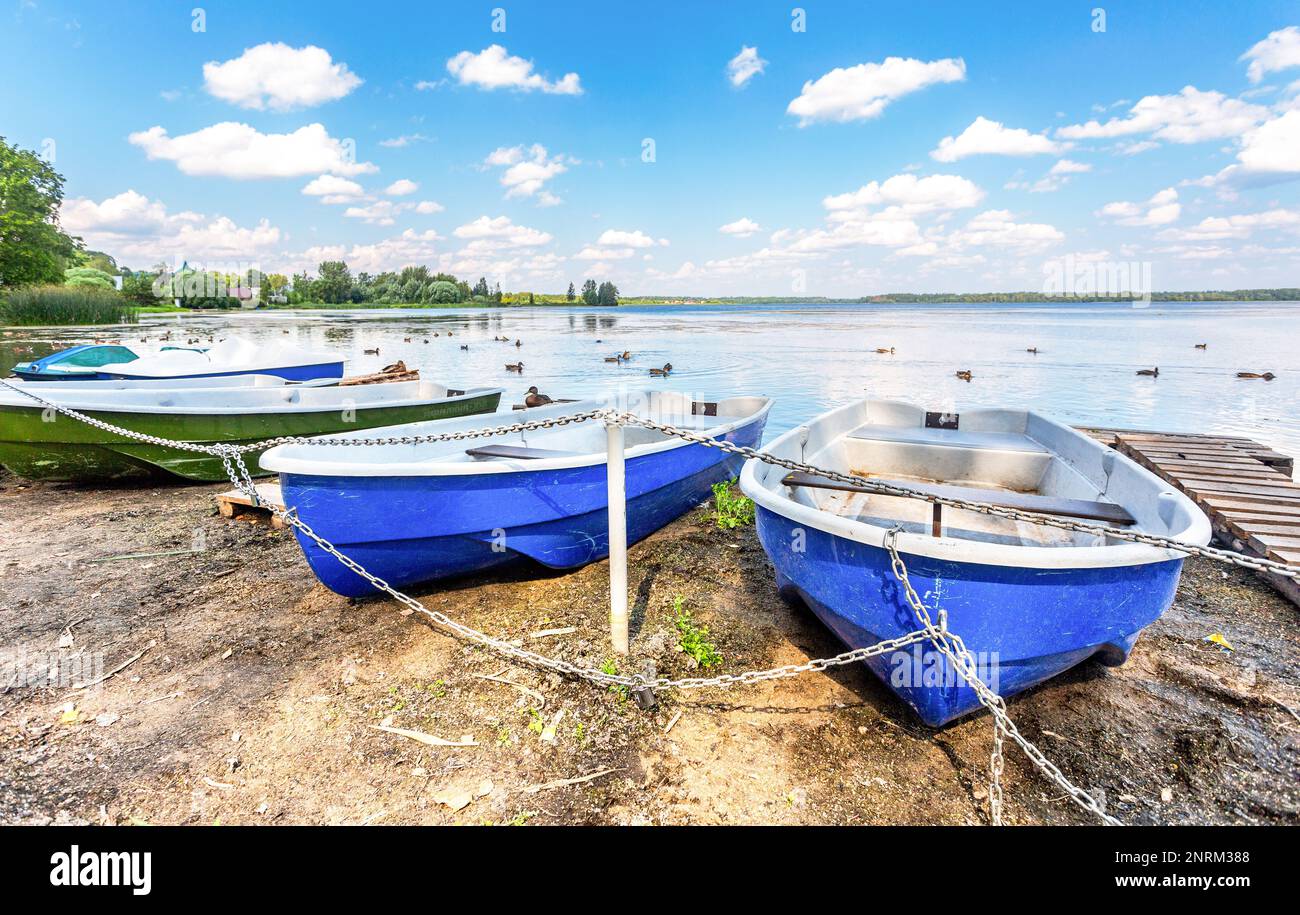 Les bateaux de plaisance en plastique sont amarrés sur la rive du lac par une journée ensoleillée d'été Banque D'Images