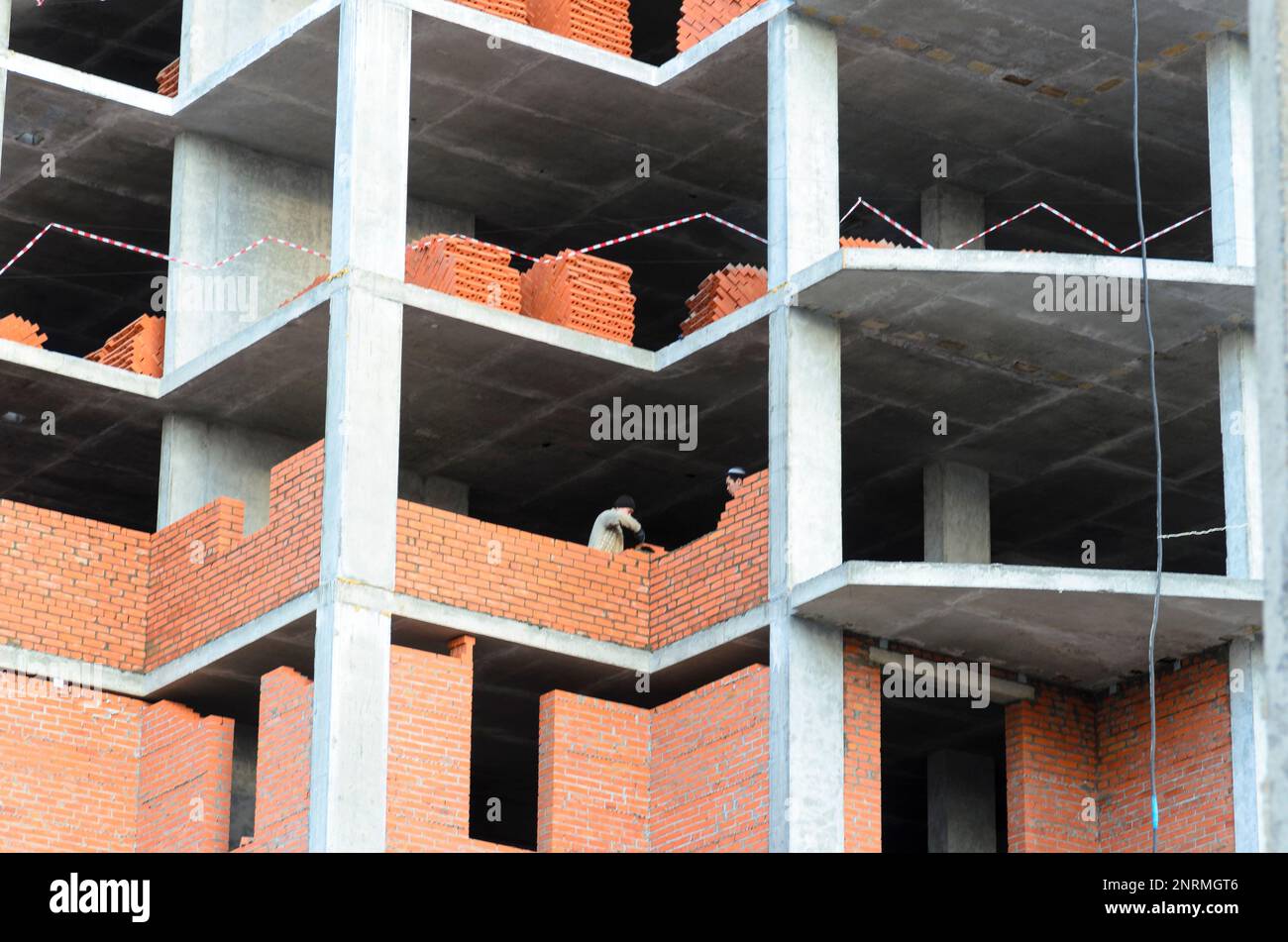 Deux constructeurs ont posé des murs de briques dans une nouvelle maison multi-appartement en construction en Russie. Banque D'Images