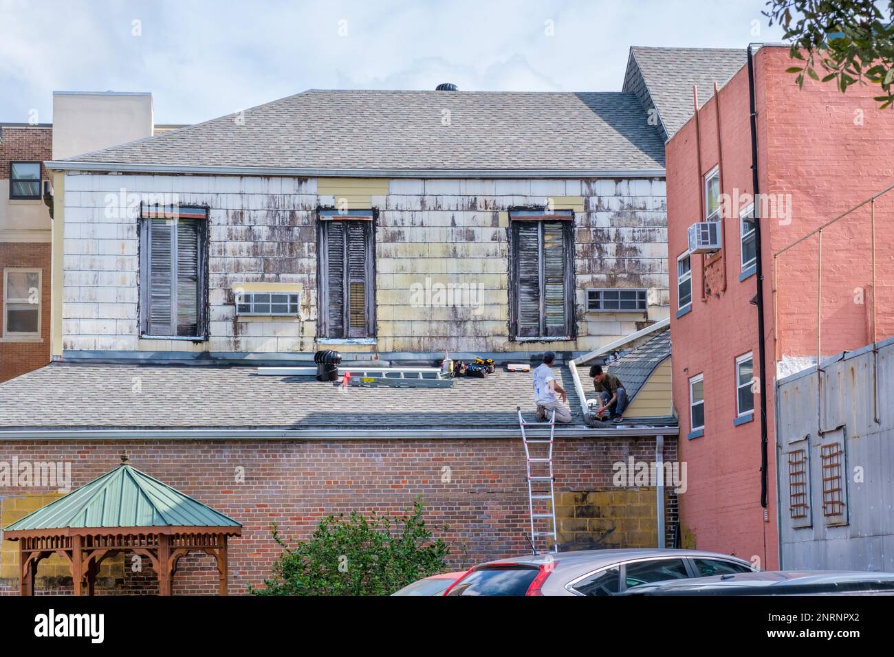 LA NOUVELLE-ORLÉANS, LA, États-Unis - 22 FÉVRIER 2023 : deux travailleurs installent une gouttière sur le toit d'un ancien bâtiment Banque D'Images