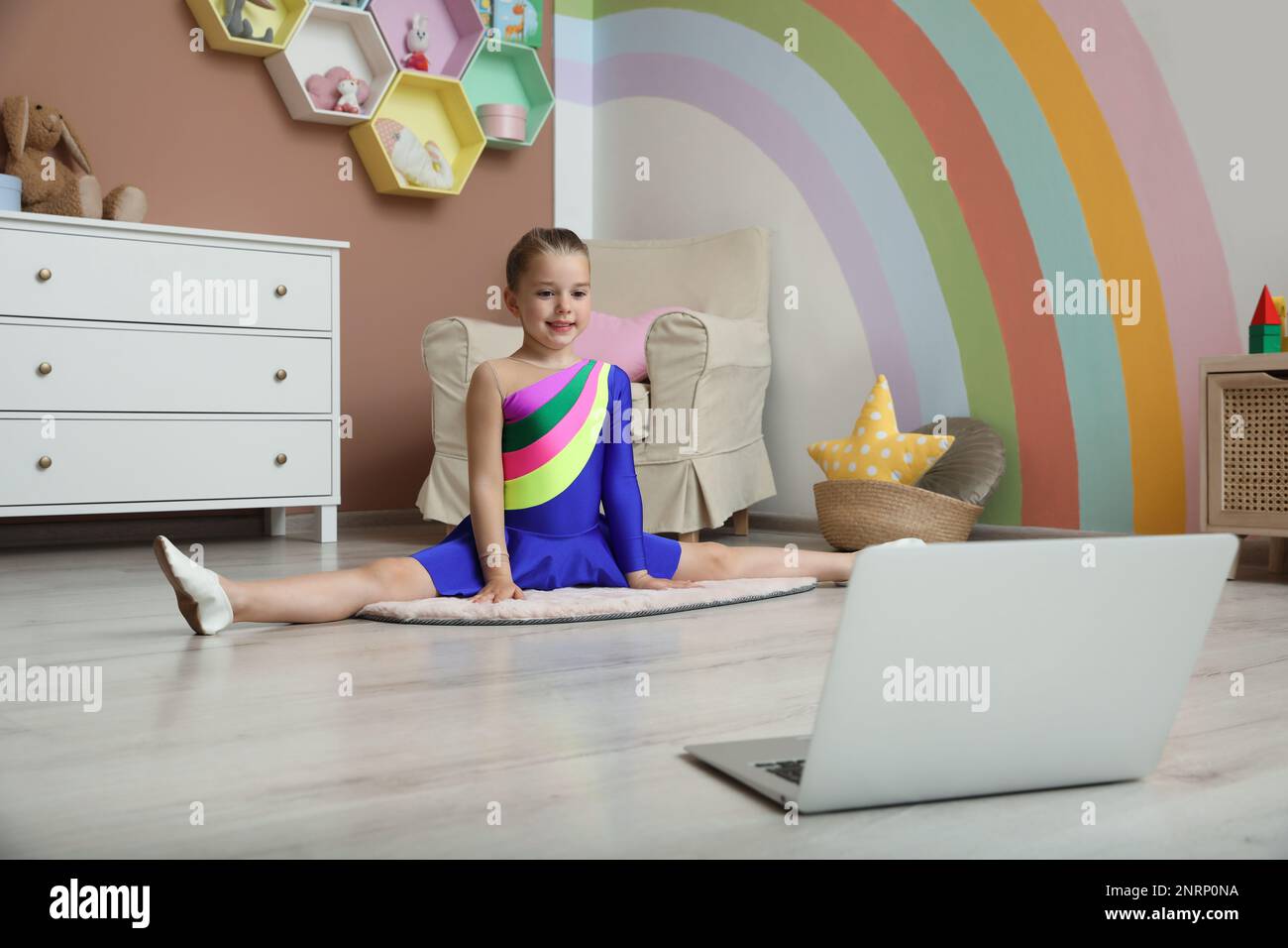 Mignonne petite fille se réchauffant avant le cours de danse en ligne à la maison Banque D'Images