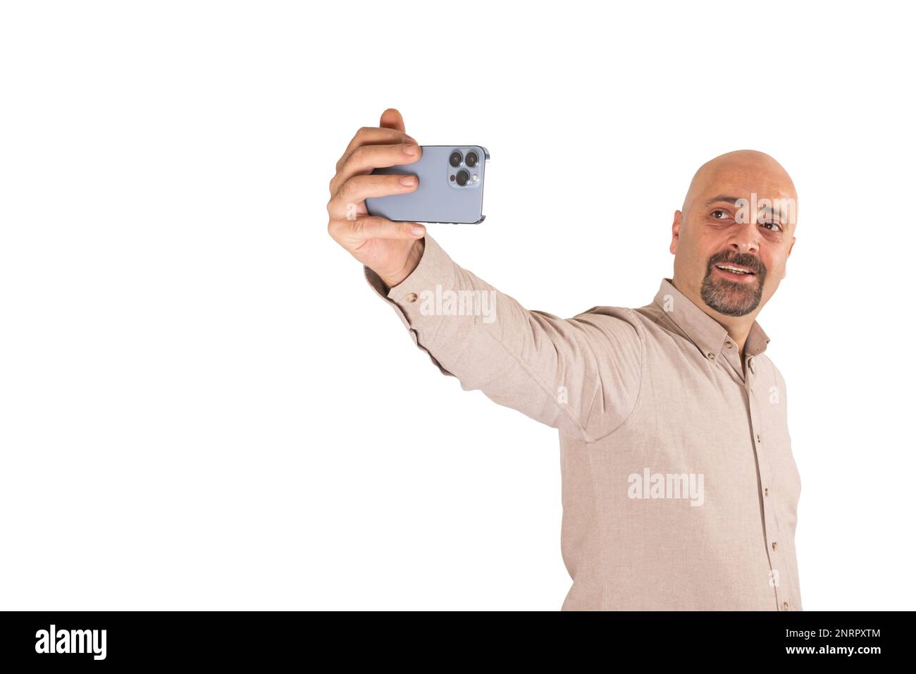 Portrait d'un homme millénaire caucasien prenant un selfie. Arrière-plan blanc isolé et debout. Tenir un smartphone moderne avec trois appareils photo. Un homme souriant. Banque D'Images