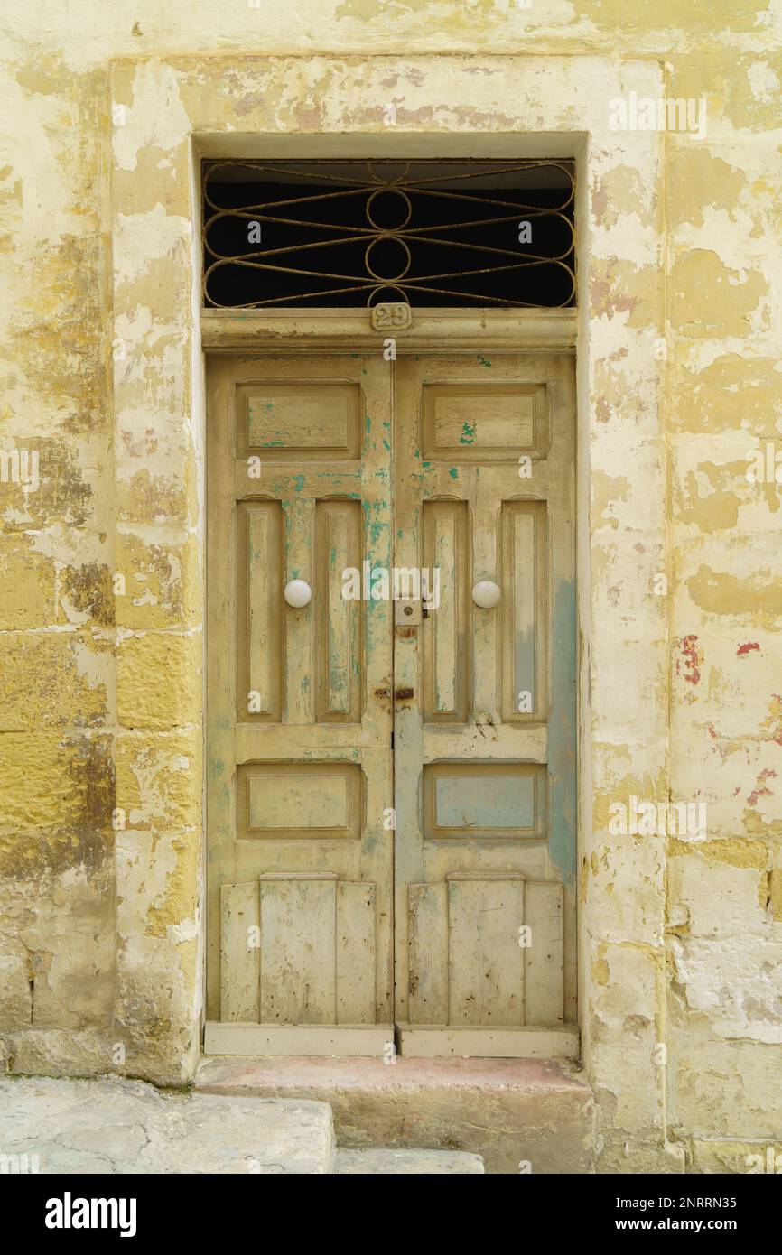 Ancienne façade de peinture pastel et style traditionnel classique en bois médiéval vintage jaune porte peinte avec des knockers à la Valette, Malte. Banque D'Images