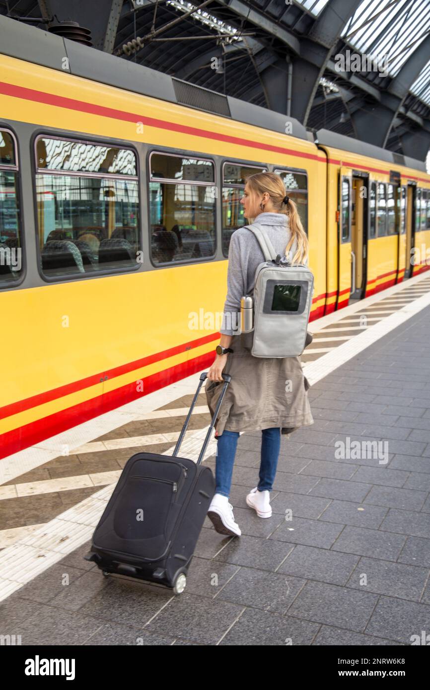 Jeune femme avec valise à roulettes sur la voie ferrée (modèle relâché) Banque D'Images