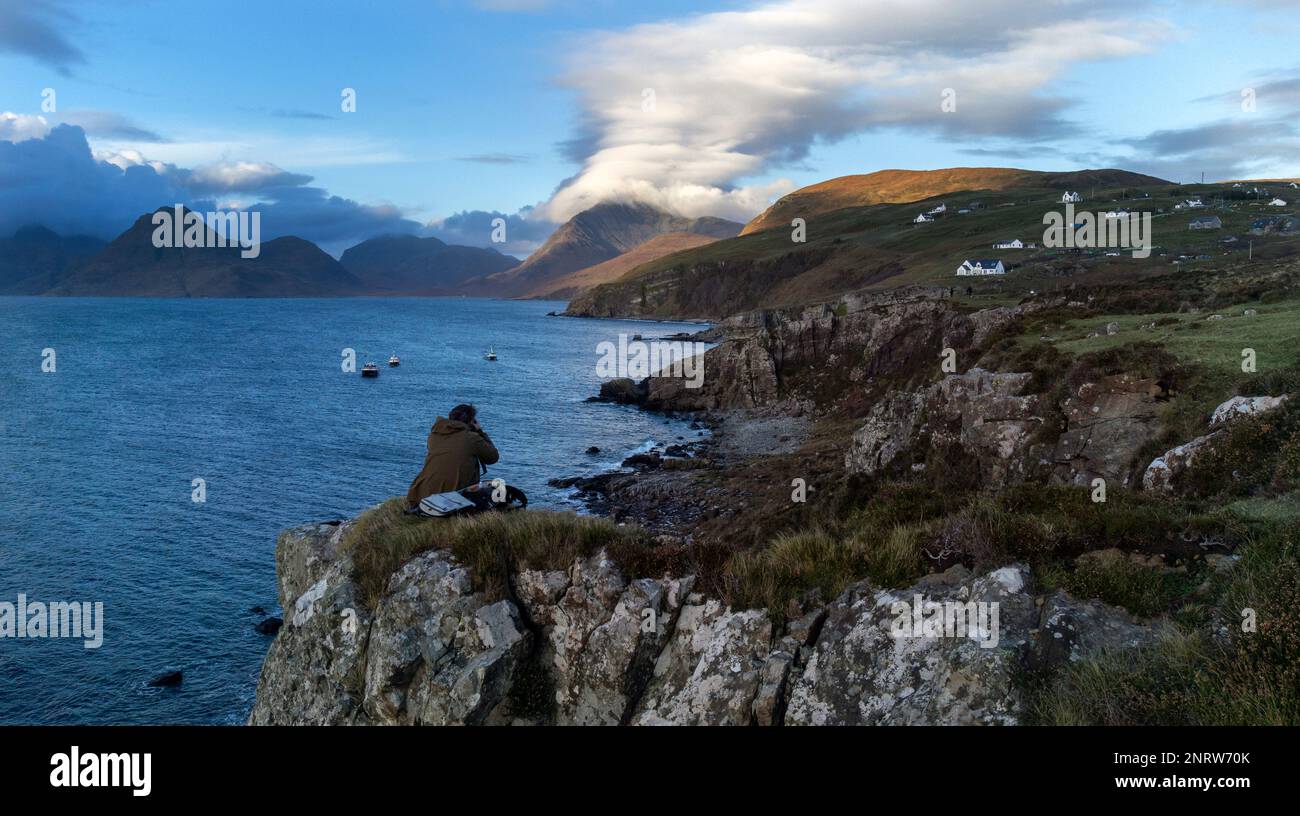 Un photographe prend des photos en regardant vers le nord-ouest à travers le Loch Scavaig vers la chaîne de montagnes Cuillin au village d'Elgol sur l'île de Skye. Banque D'Images