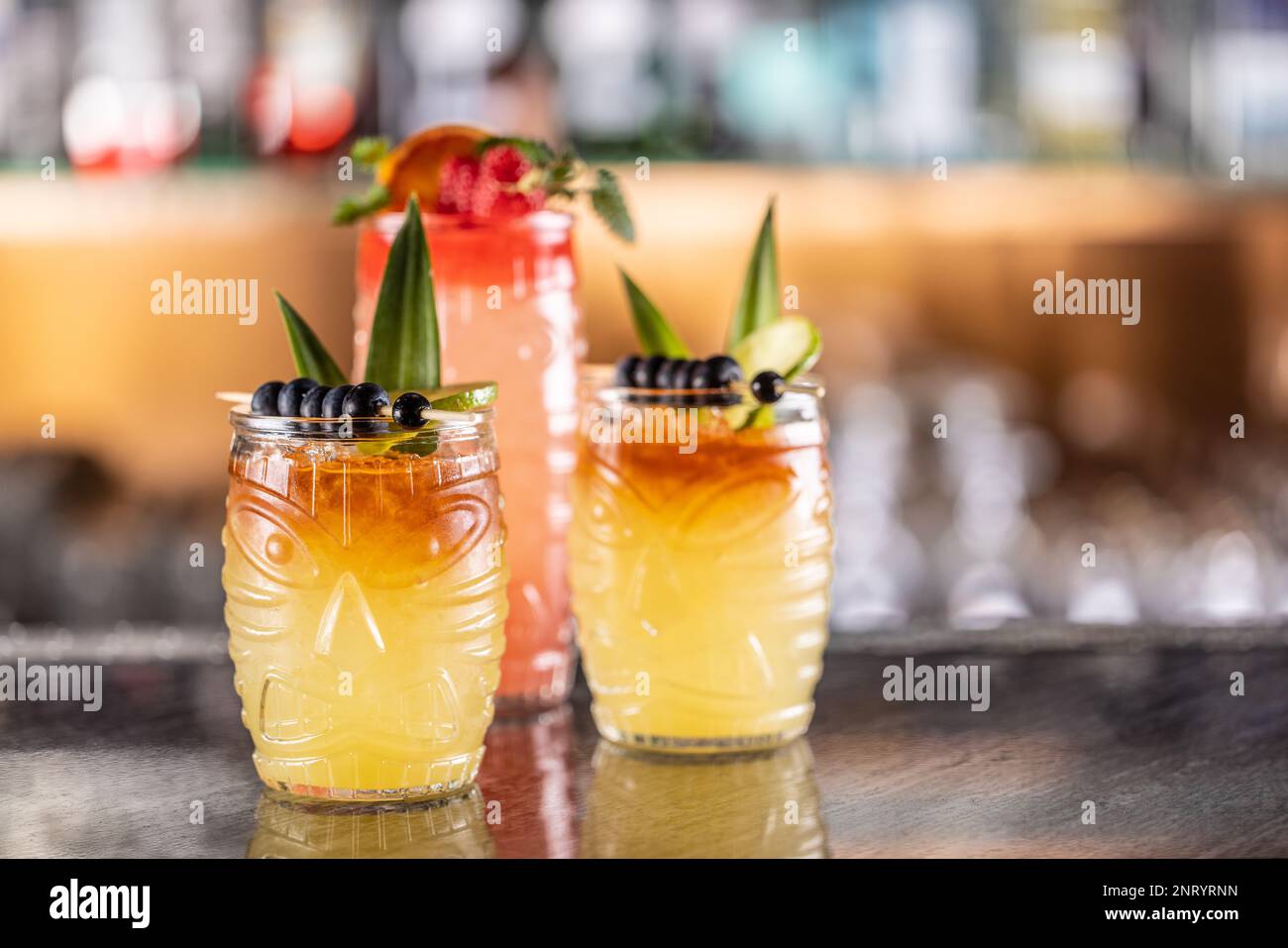 Cocktails mai tai dans des verres hawaïens garnis d'ananas, de bleuets et de fraises sur le comptoir du bar. Banque D'Images