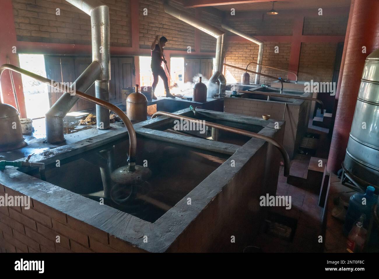 Un travailleur a tendance à avoir un mezcal encore dans une distillerie artisanale de mezcal à Santiago Matatlan, Oaxaca, Mexique. Ces petites entreprises familiales font mezcal dans TH Banque D'Images