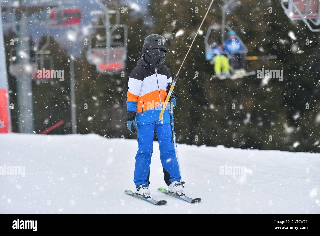 Atteindre de nouvelles hauteurs - un enfant à skis monte la montagne avec un tour sur le télésiège Banque D'Images