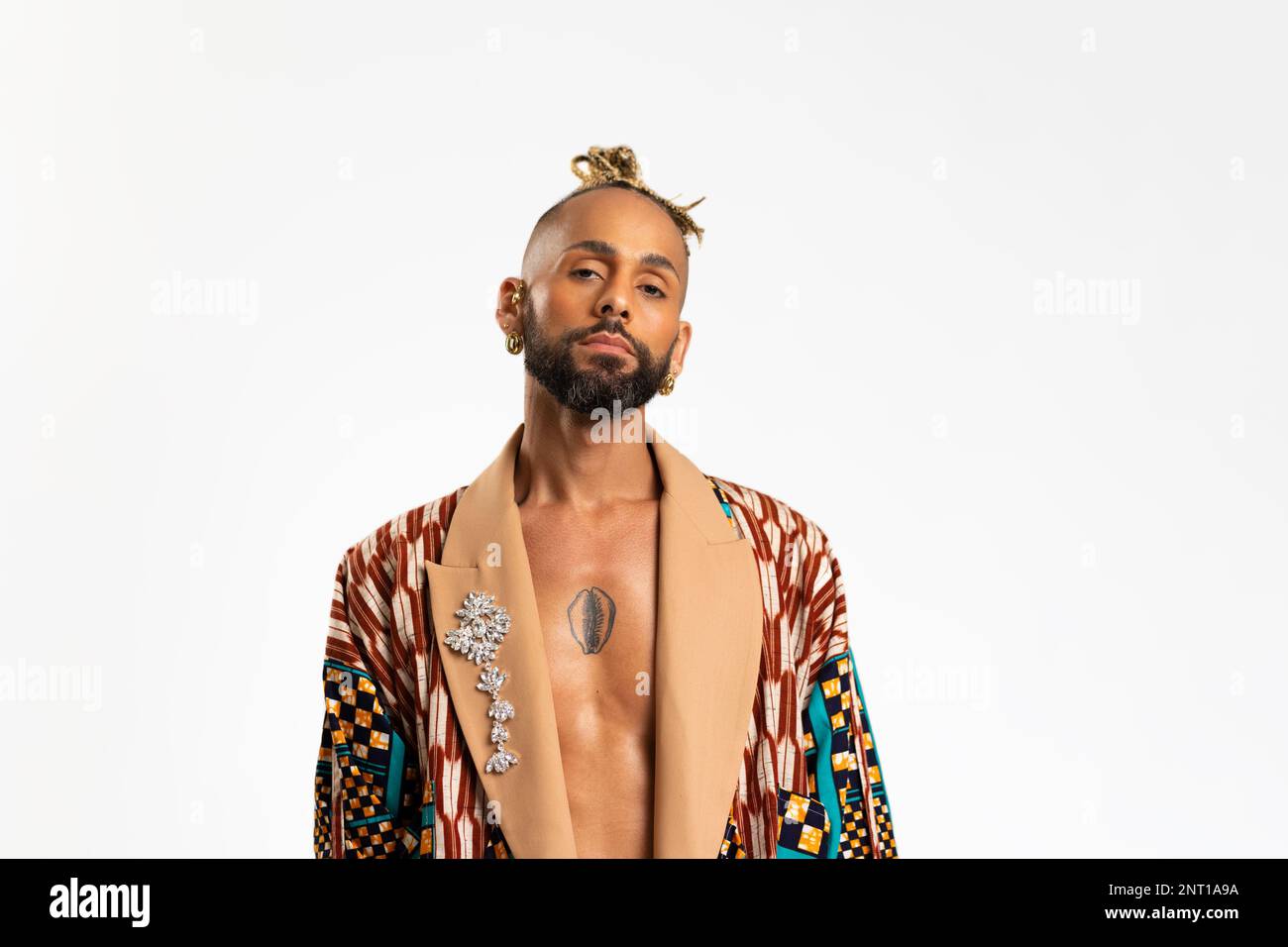 Homme gay noir confiant, isolé sur fond blanc, habillé d'une veste audacieuse et colorée ornée d'une broche élégante. Dégage un sentiment de fierté et d'individualité. Pouvoir de diversité du style personnel Banque D'Images