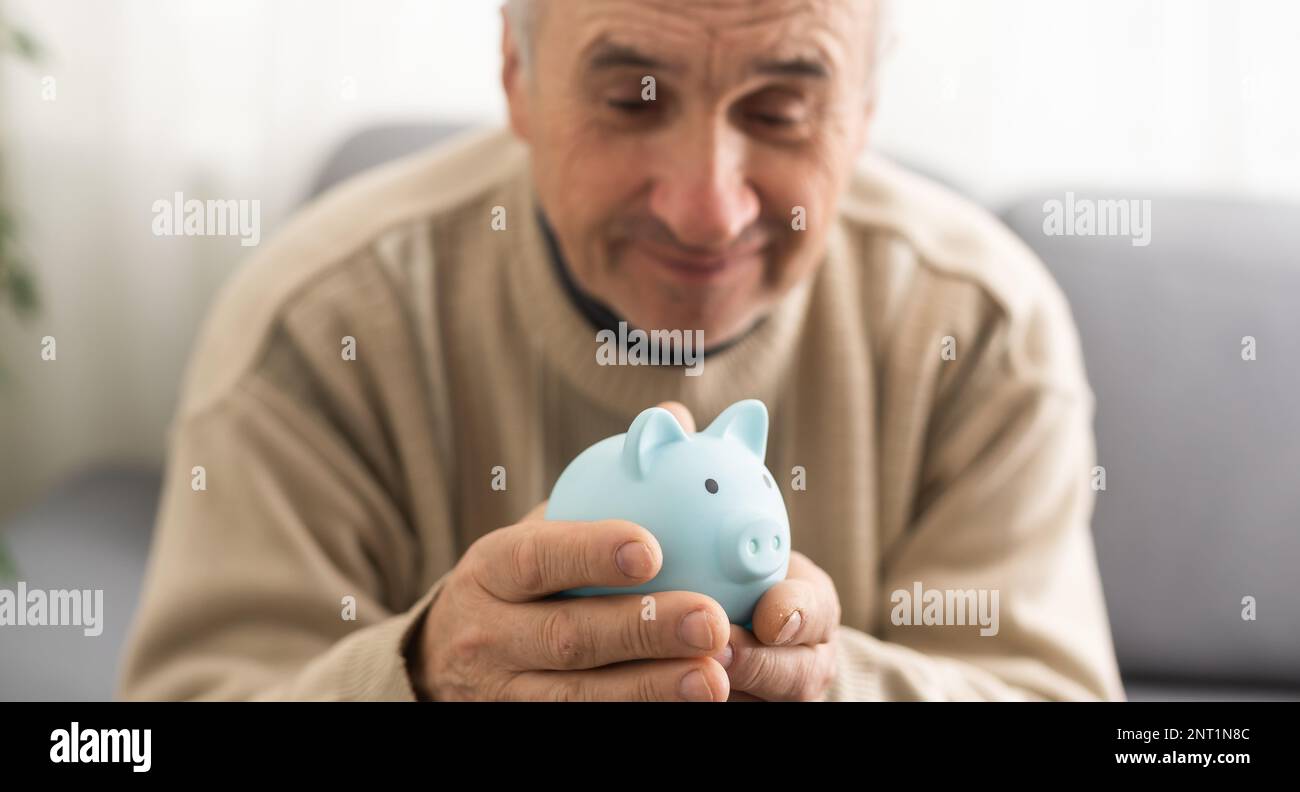 un homme âgé tient une banque de porc Banque D'Images