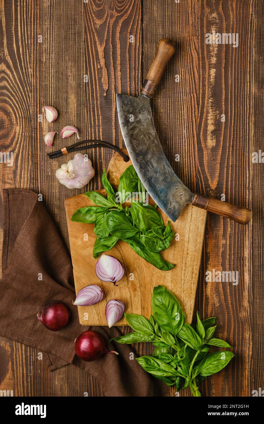 Préparation de salade rustique simple. Basilic, oignon et ail sur planche à découper en bois Banque D'Images